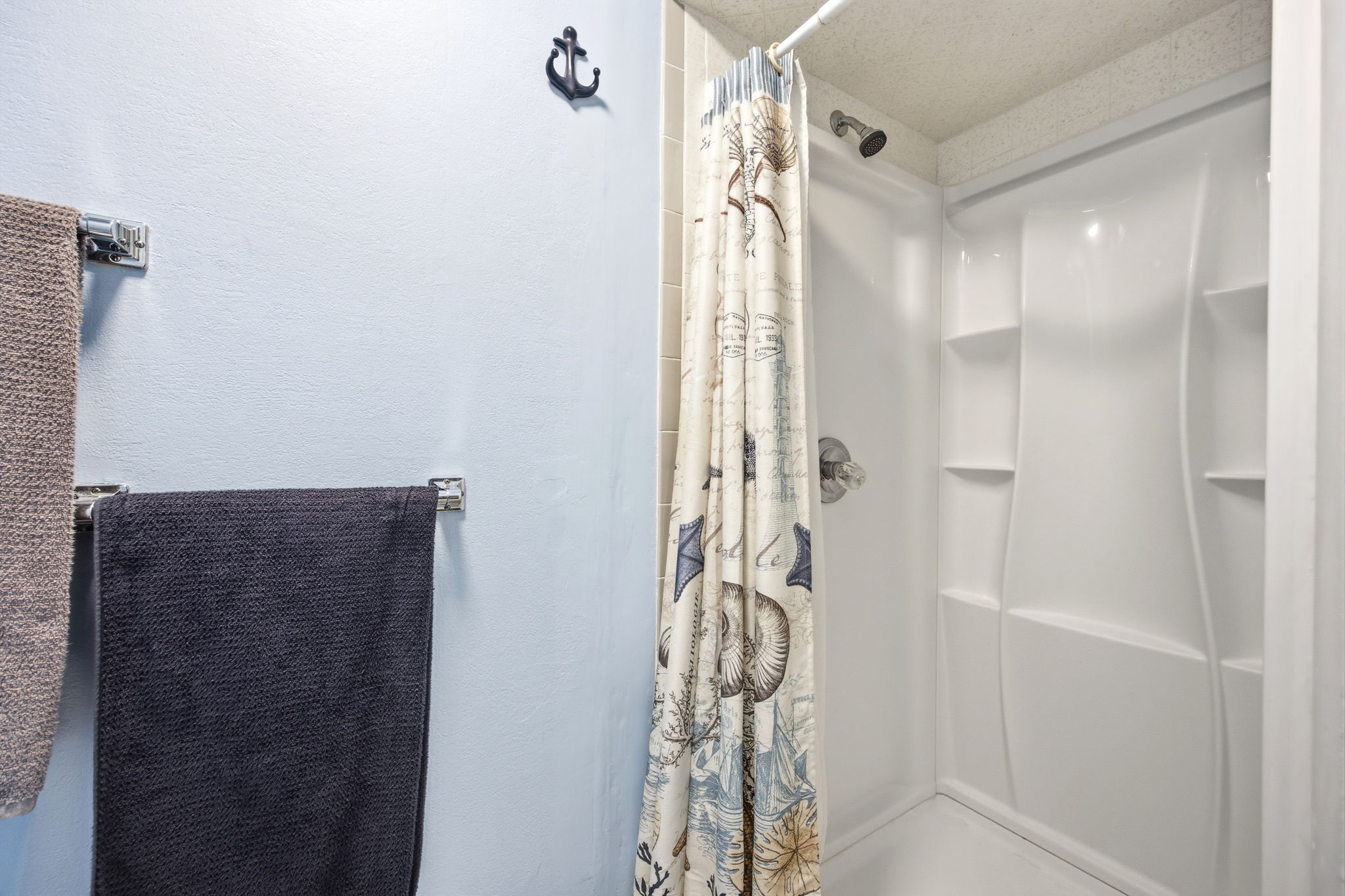 Bright white shower enclosure featuring a fixed shower head and built-in shelving