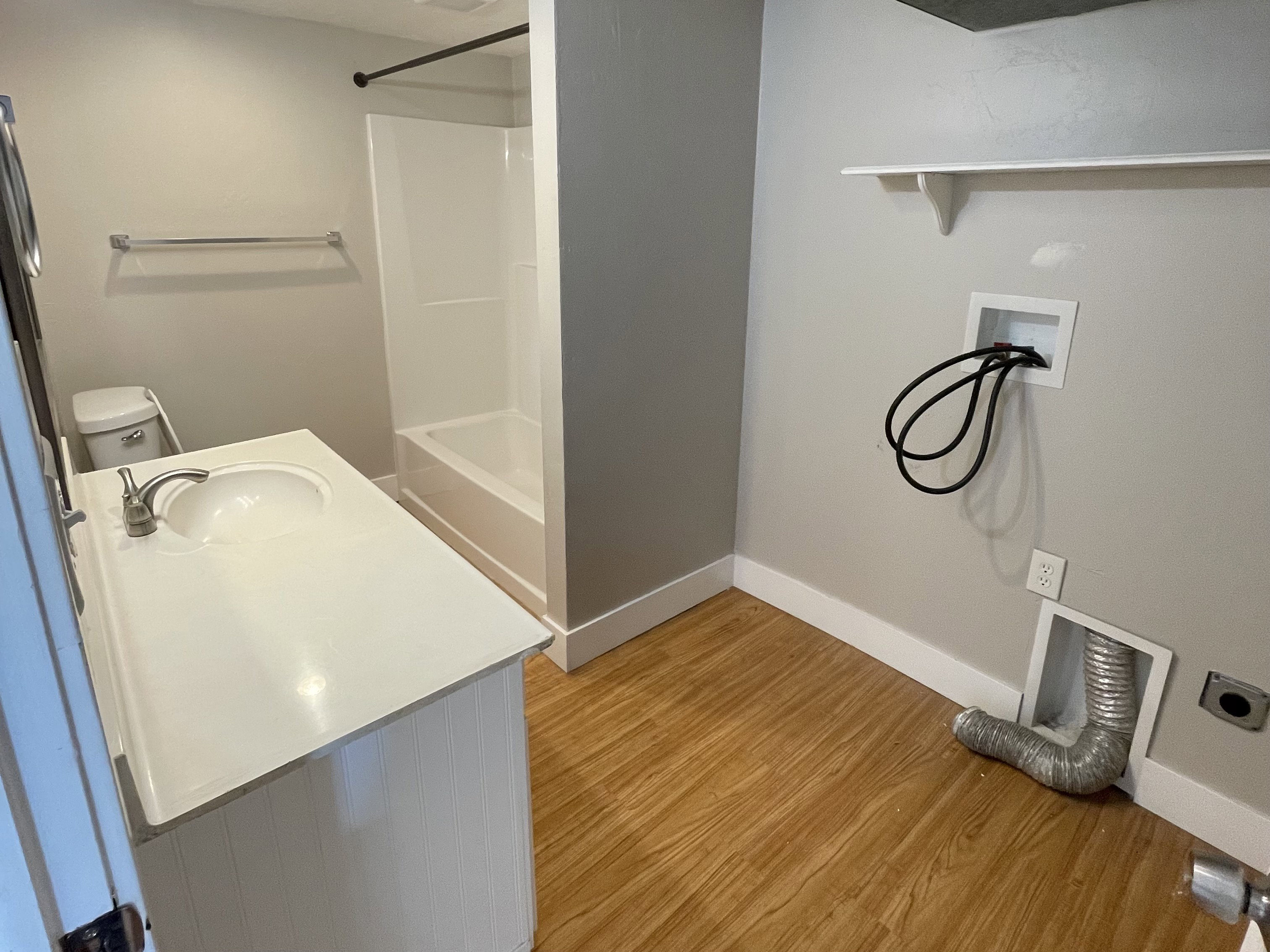 Bathroom featuring a white vanity with integrated sink, chrome faucet, toilet, and a white tub/shower combination