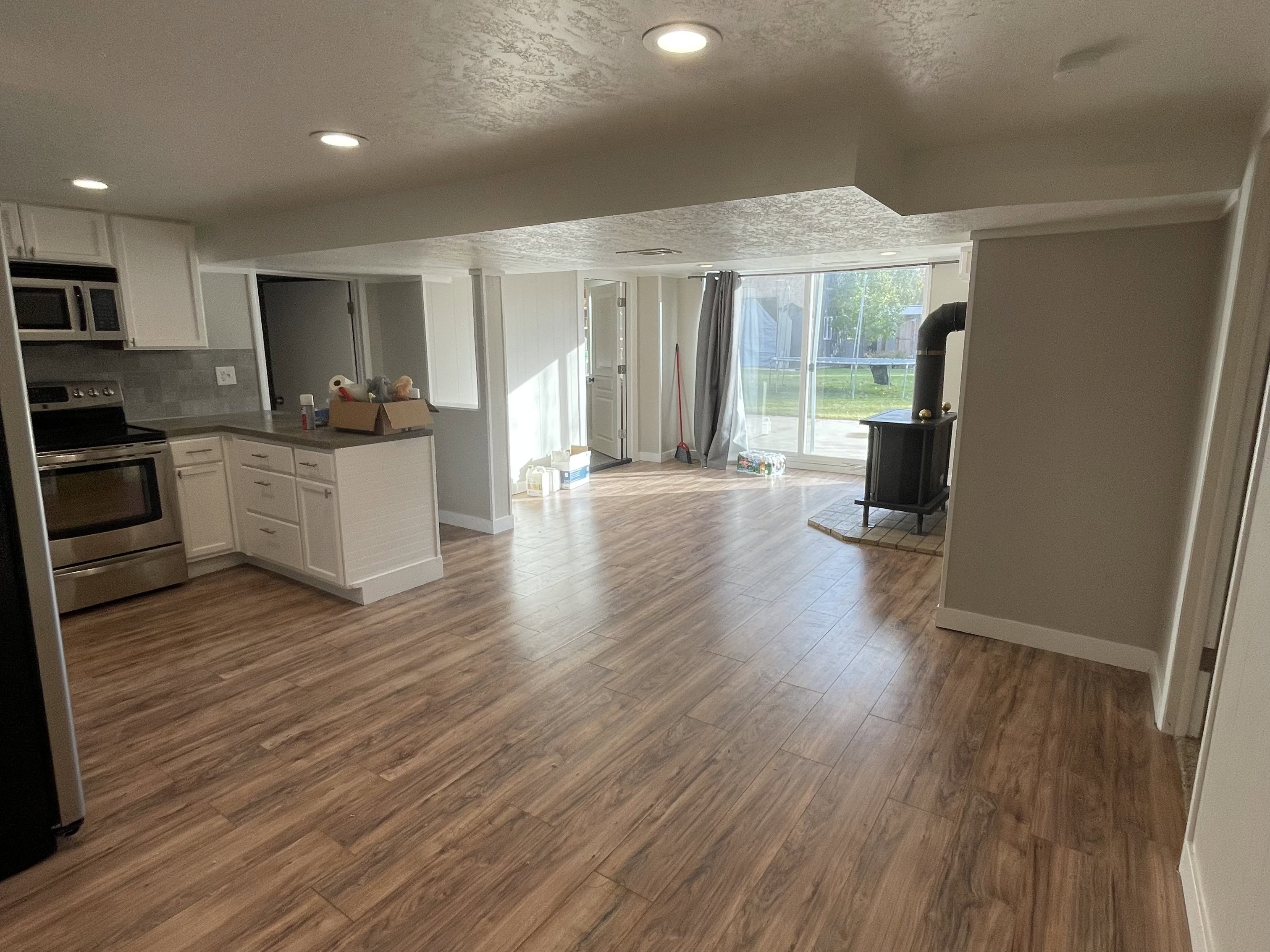 Kitchenette with white shaker cabinetry, stainless steel appliances, and wood-finish flooring