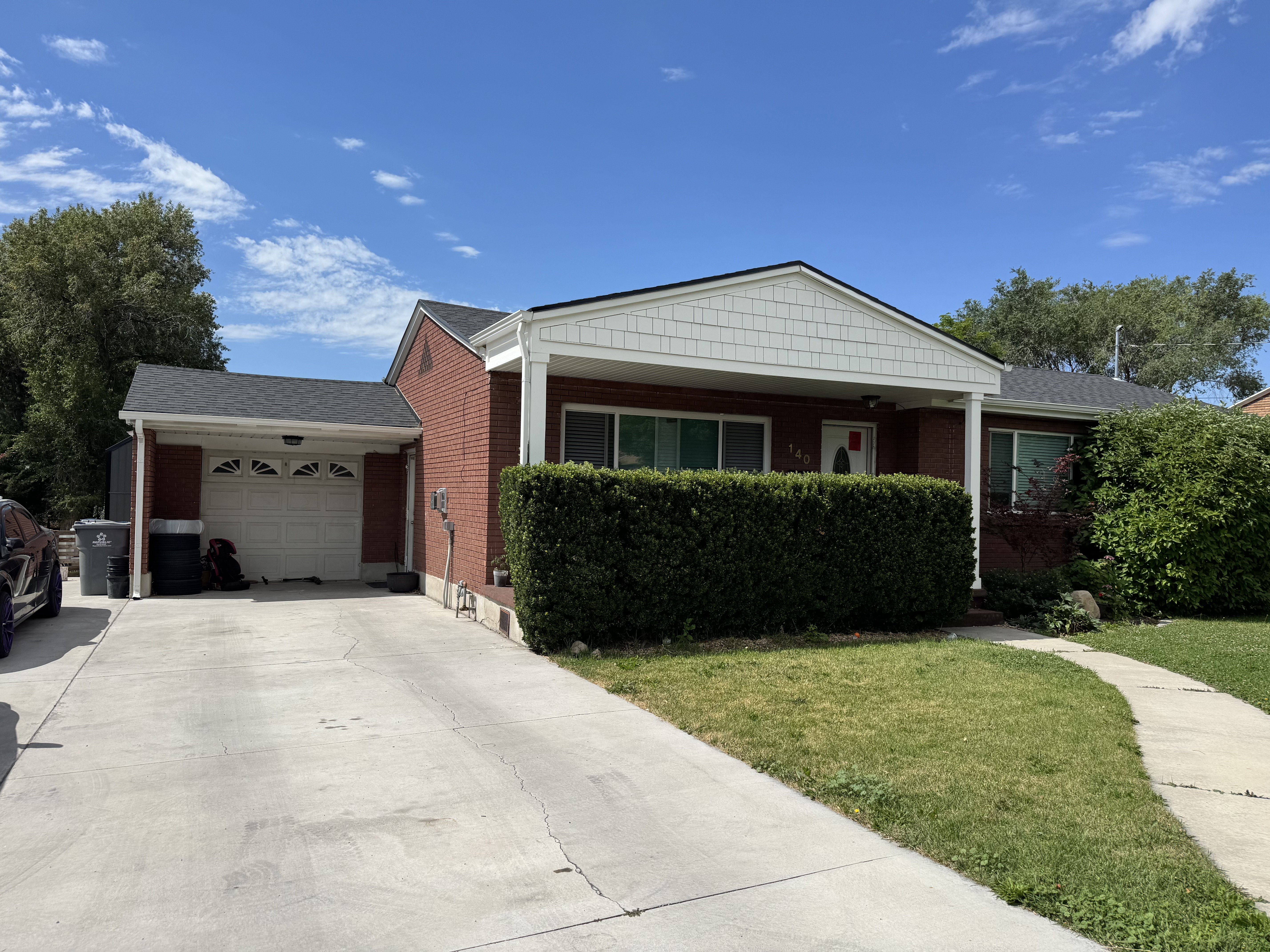 Brick exterior featuring a covered entry, attached garage, and a concrete driveway