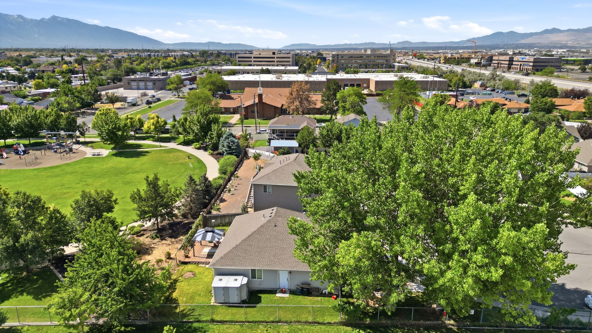 Expansive green space featuring a playground, paved walking path, and mature trees