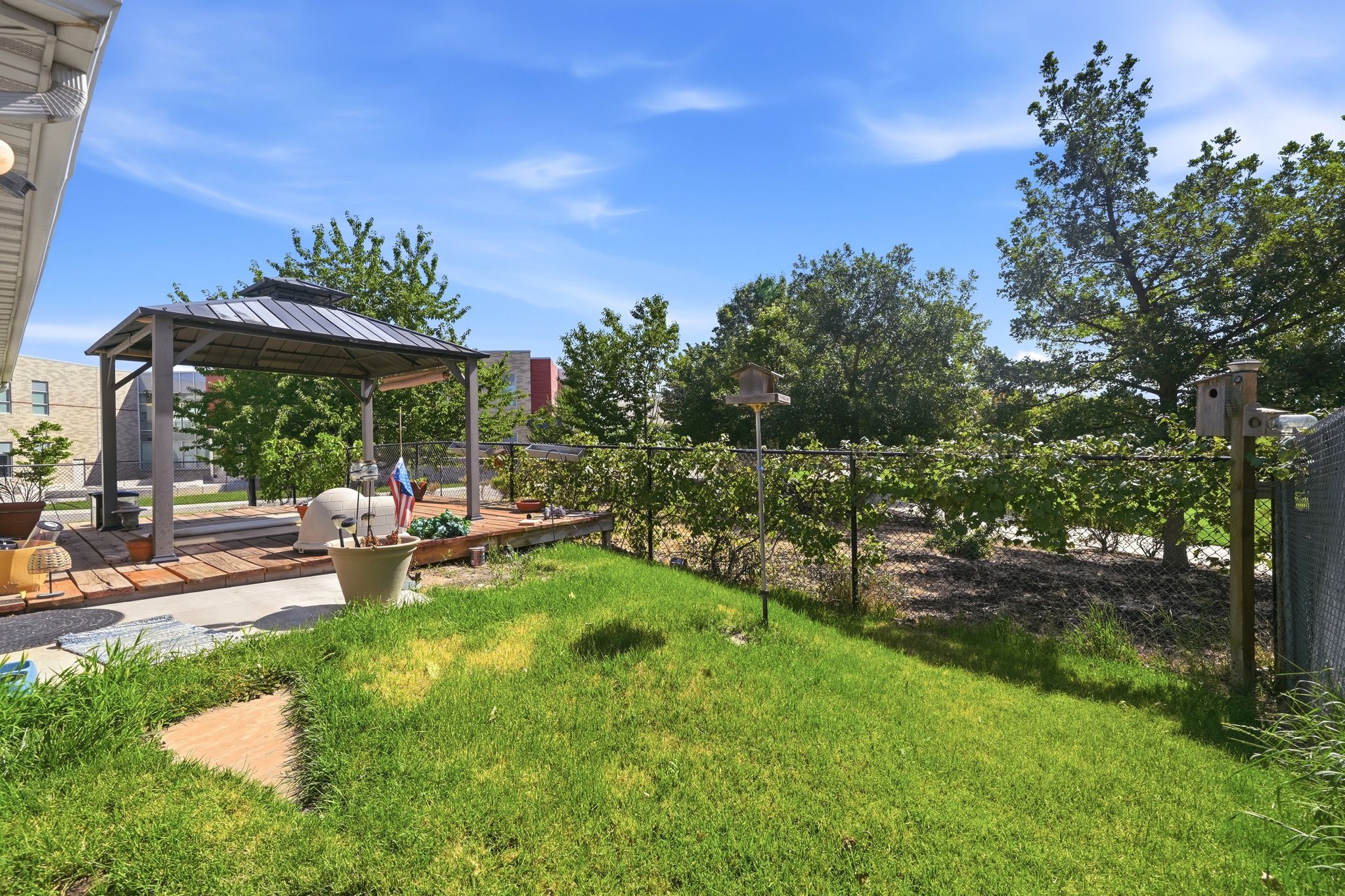 Expansive lawn area featuring a decorative stone path and chain-link fencing with established foliage