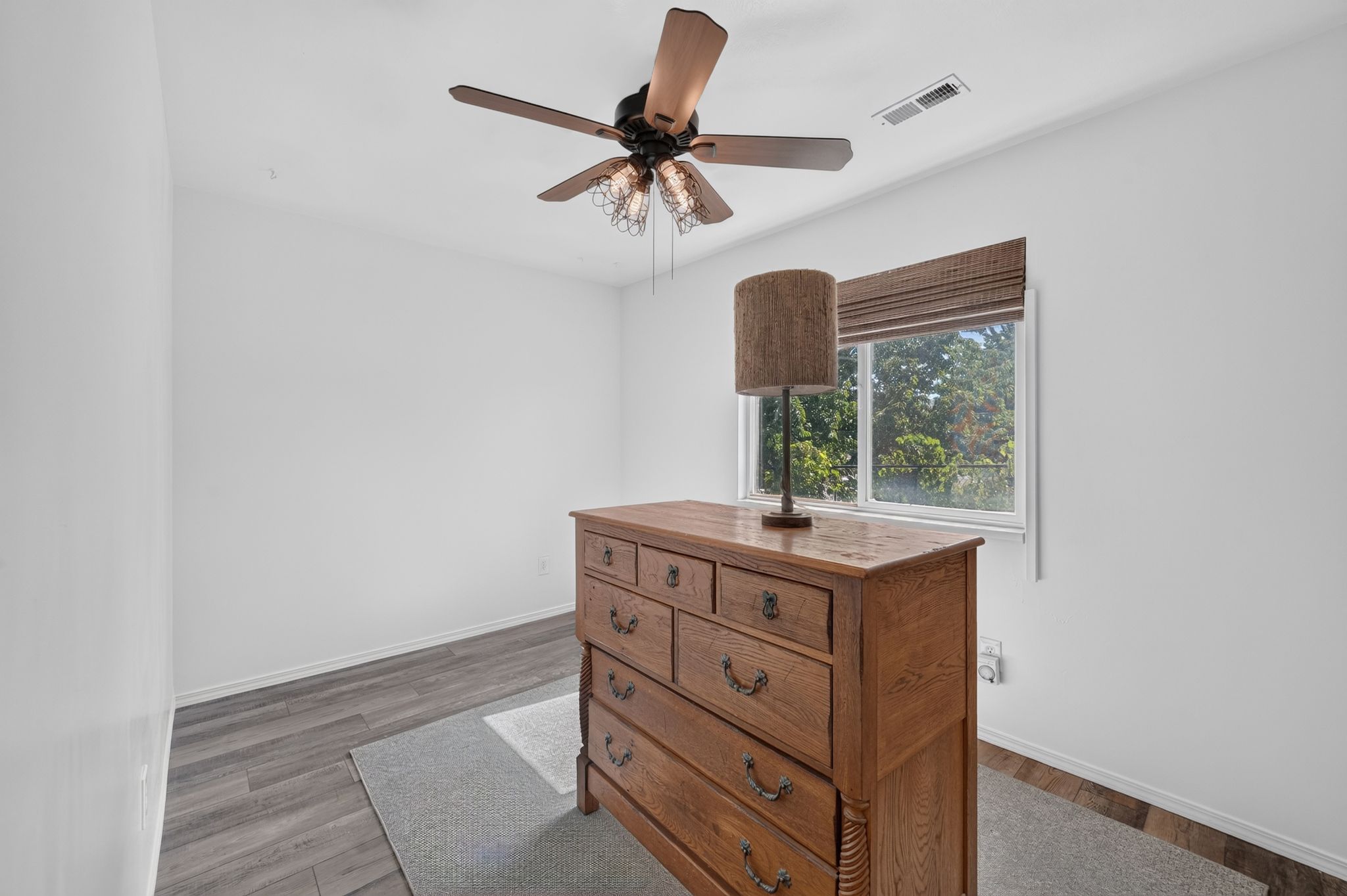 Bright room featuring wood-finish flooring and a window with a woven shade