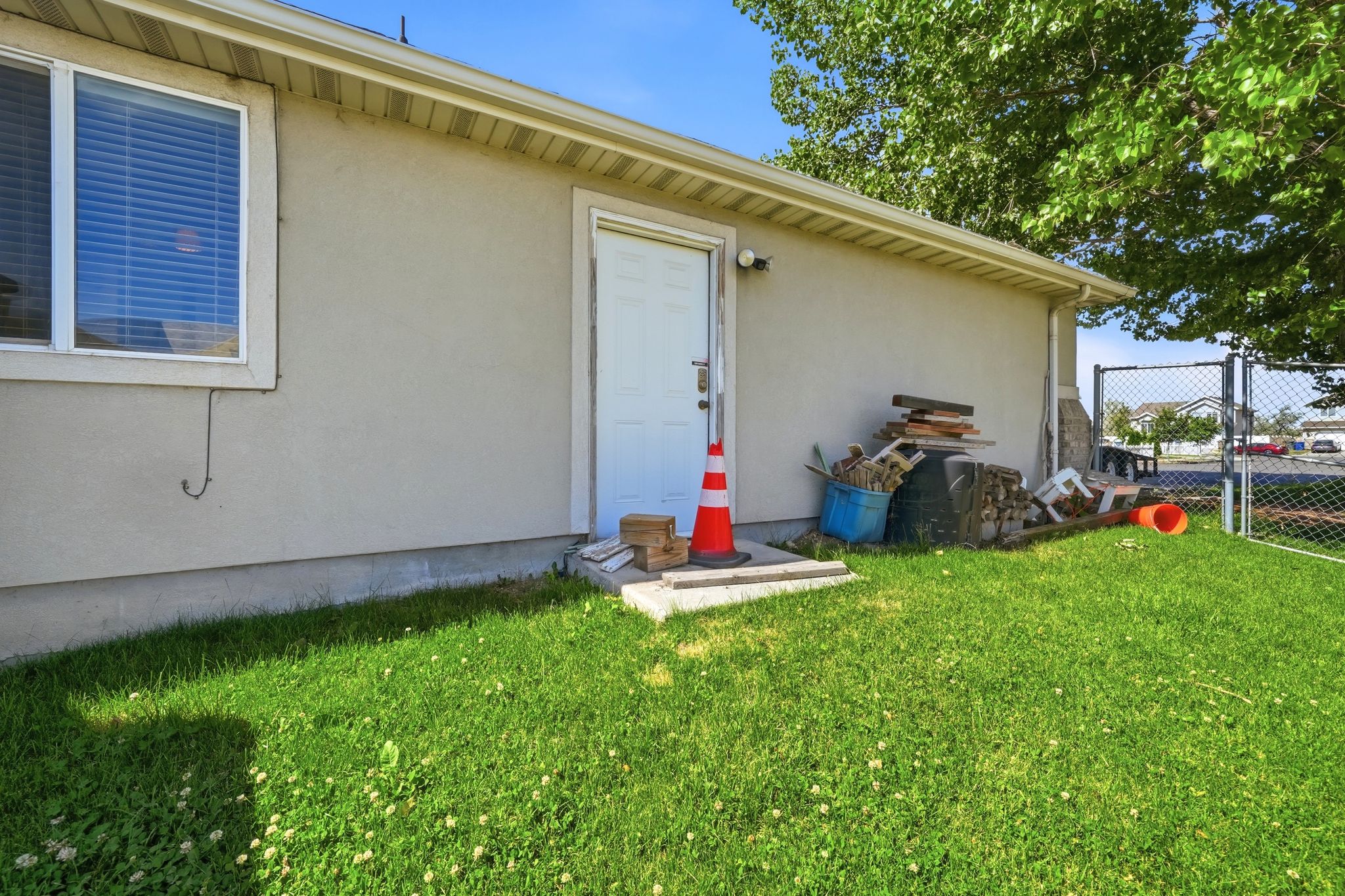 Manicured lawn area with a stucco exterior, white trim, and a chain-link fence