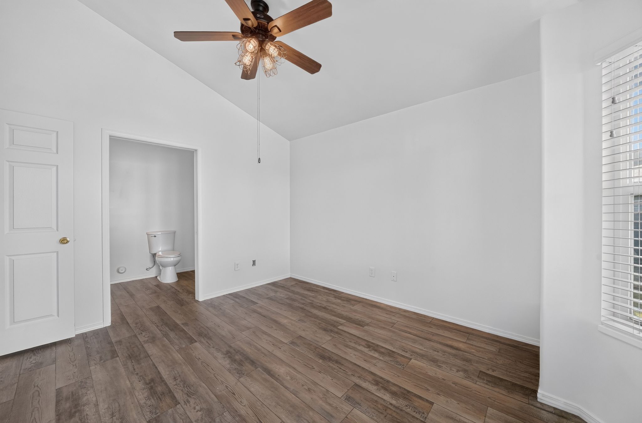 Room with wood-finish flooring, white walls, and a ceiling fan with integrated lighting