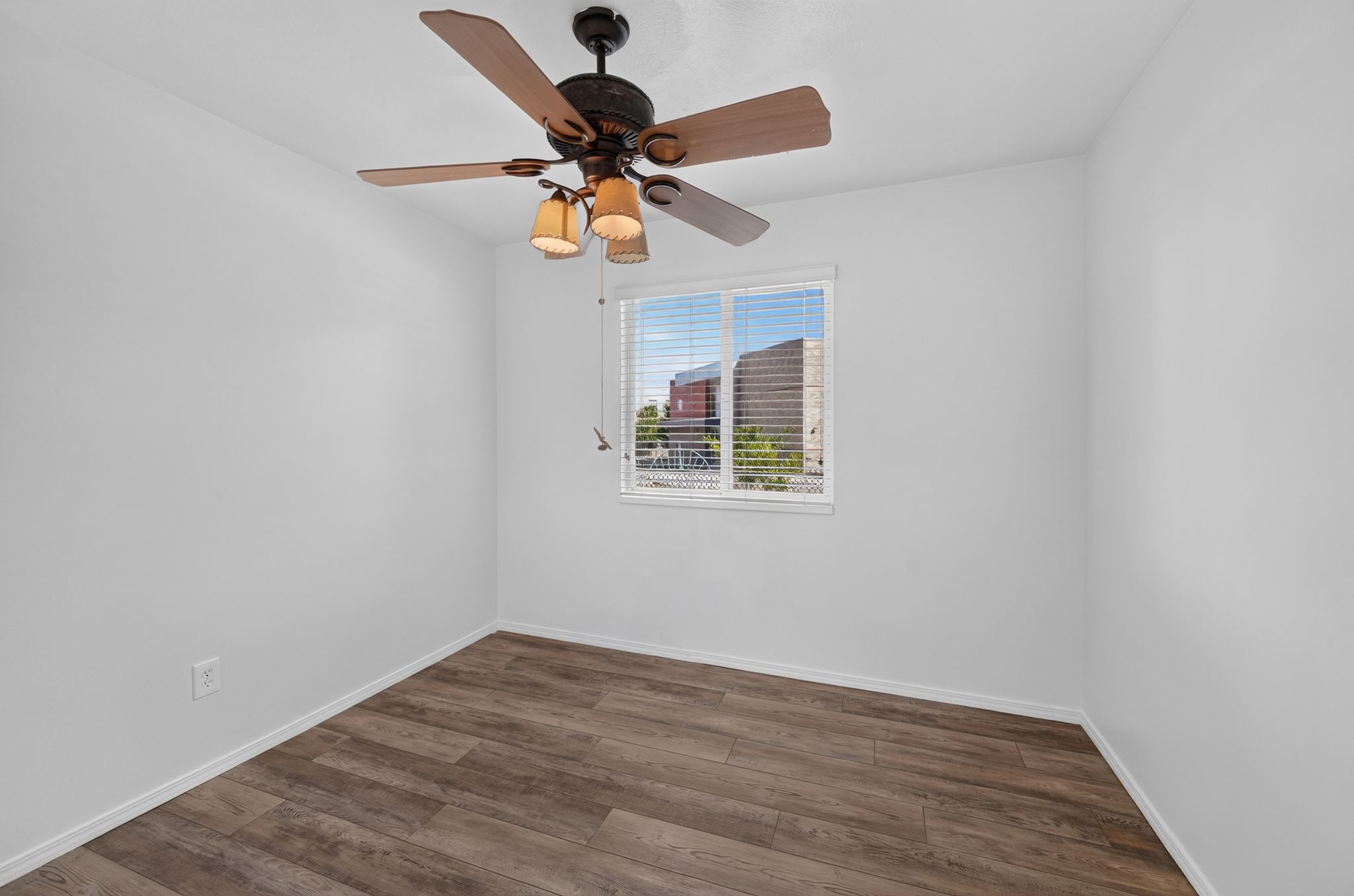 Room featuring wood-finish flooring, a window with horizontal blinds, and a ceiling fan with integrated lighting