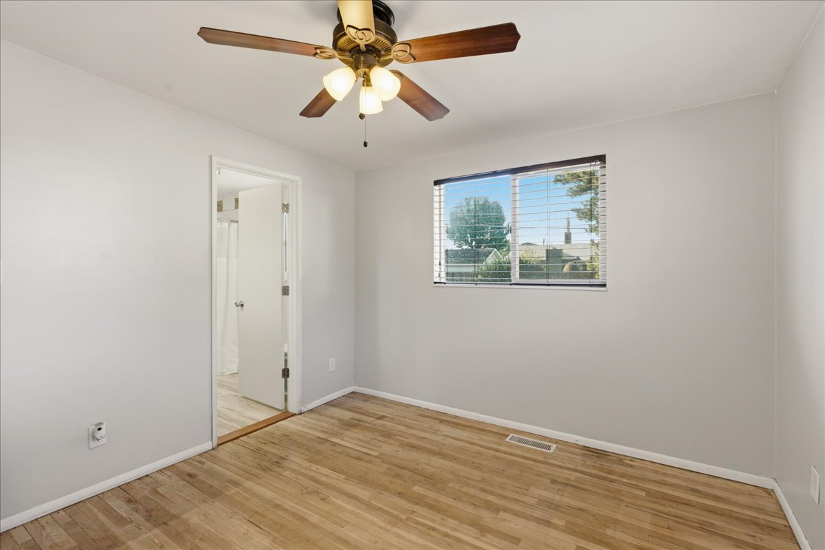 Room featuring light wood-finish flooring, a ceiling fan with light fixture, and a window with horizontal blinds