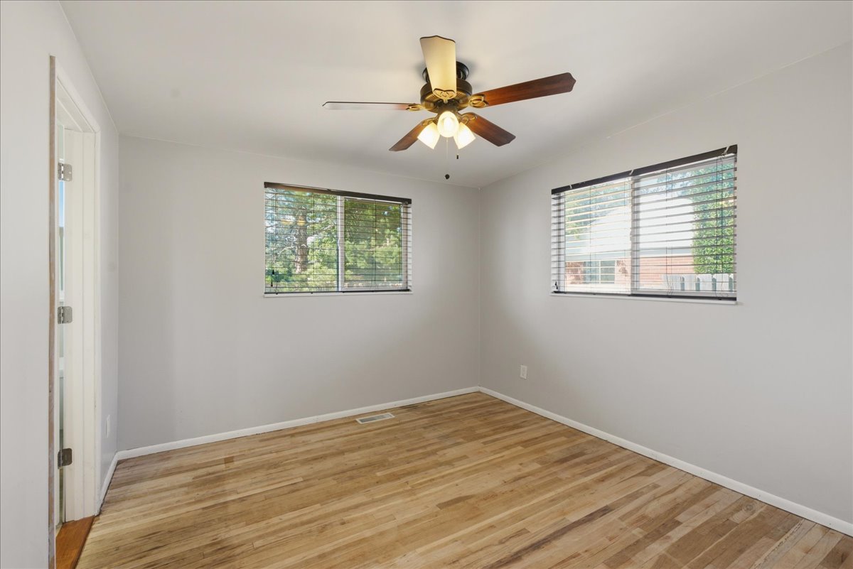 Light gray walls, wood-finish flooring, and a ceiling fan with light fixture