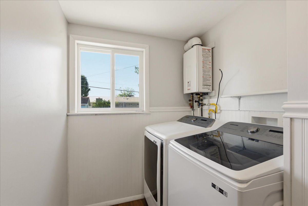 Dedicated utility space featuring a wall-mounted tankless water heater, a window with natural light, and beadboard paneling