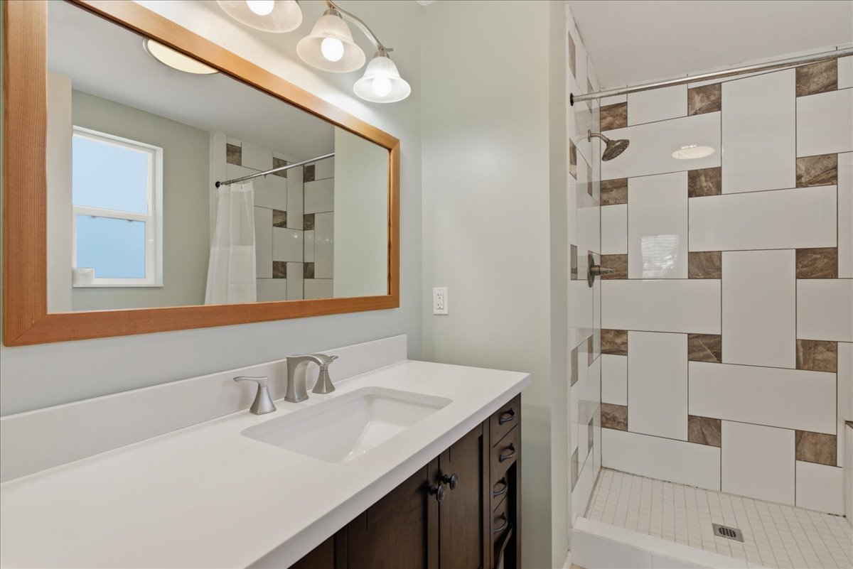 Bathroom featuring a dark wood-finish vanity with a white countertop and undermount sink, brushed nickel faucet, and a large wood-framed mirror