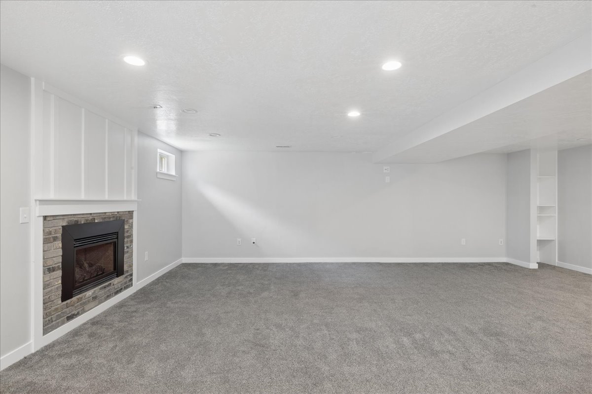 Spacious room featuring a fireplace with a stone surround, a white mantel, and board and batten wall detailing