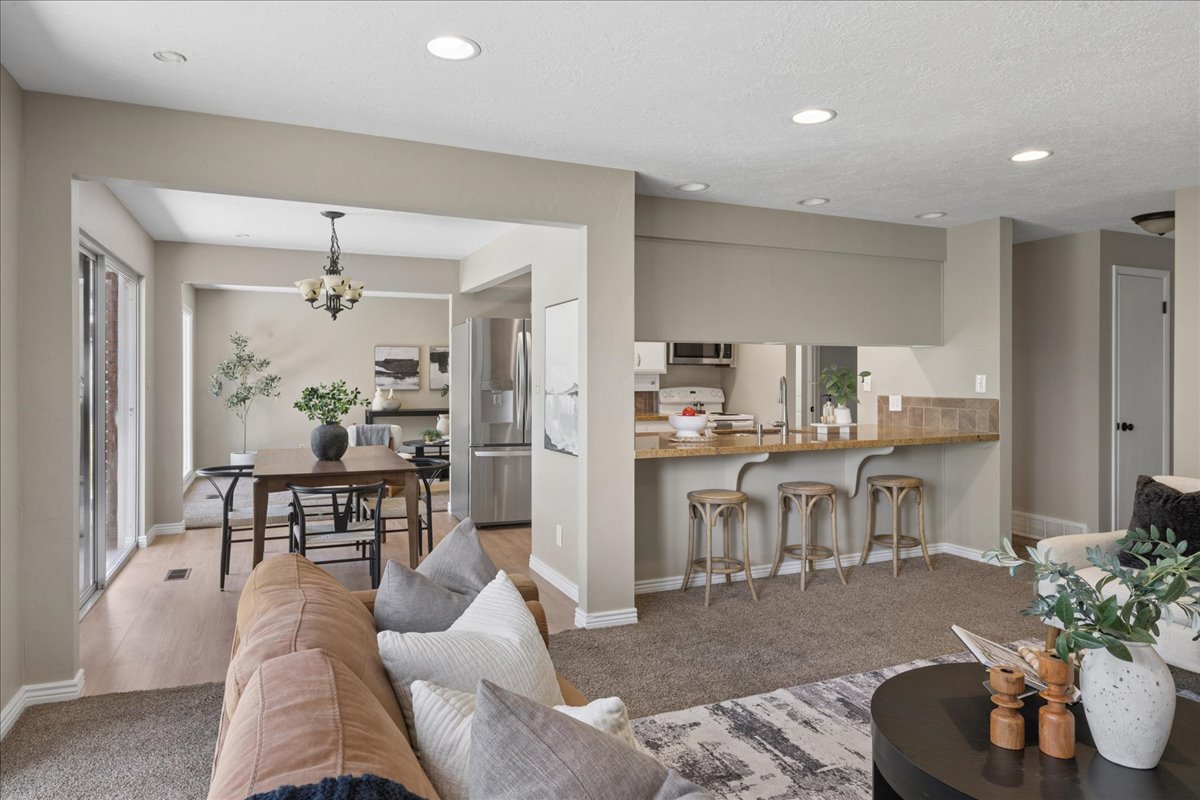 Open concept living area with recessed lighting, wood-finish flooring in the dining area, and a kitchen pass-through with a breakfast bar