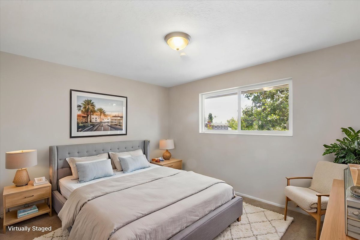 Bedroom featuring a flush-mount ceiling light, a large window, light-colored walls, and carpeting