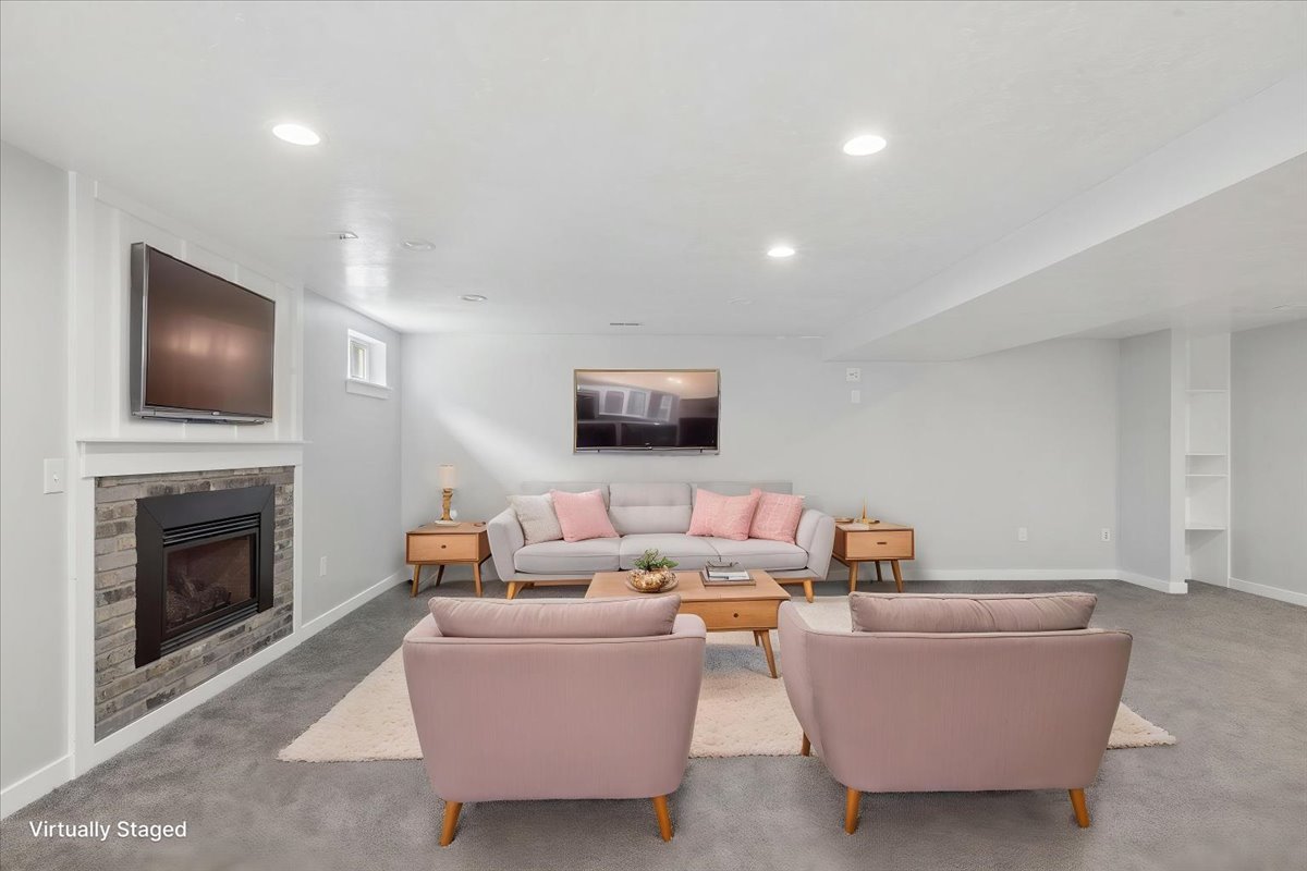 Spacious living area featuring a built-in fireplace with stone surround, recessed lighting, a window, and built-in shelving