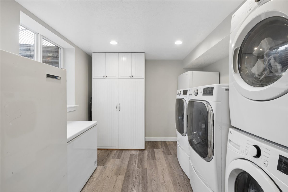 Utility area featuring wood-finish flooring, recessed lighting, white wall cabinetry, and a window