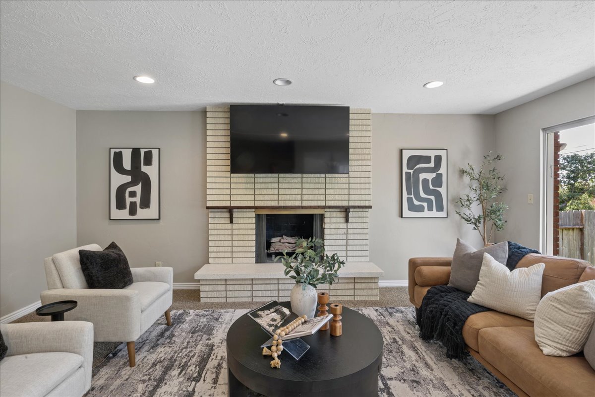 Living area featuring a brick-surround fireplace with a wood mantel, recessed lighting, neutral wall tones, and a sliding glass door
