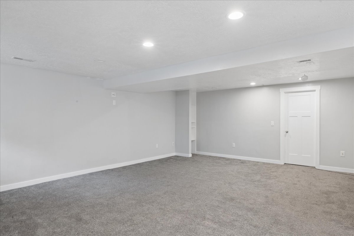 Spacious room featuring gray carpet flooring, white baseboards, and light gray walls