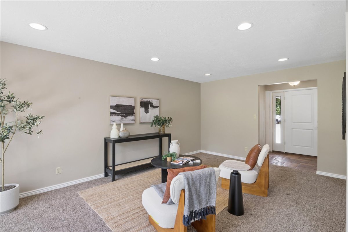 Carpeted living area featuring recessed lighting, neutral wall tones, and white baseboards