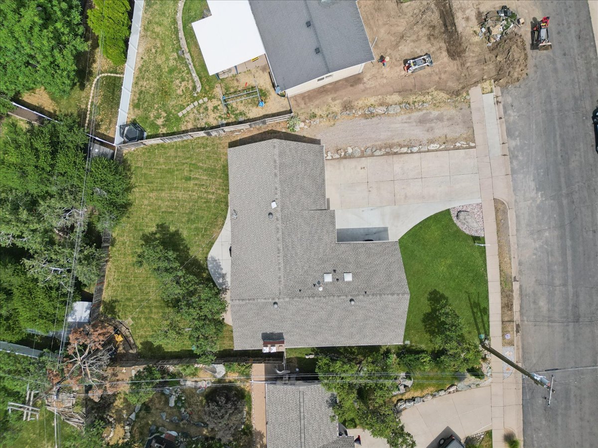 Expansive property featuring a grey shingle roof, concrete driveway, and established green lawn areas