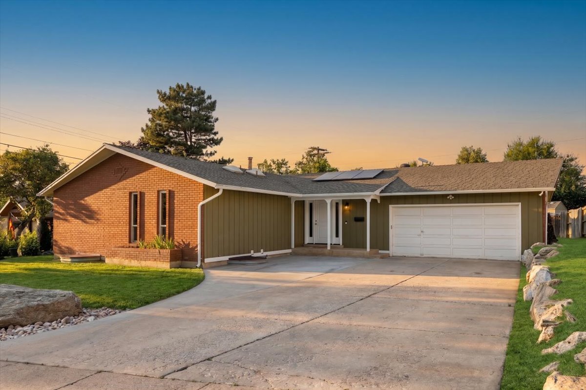 Single-story residence featuring brick and siding exterior, an attached two-car garage, a concrete driveway, a covered front porch, and solar panels