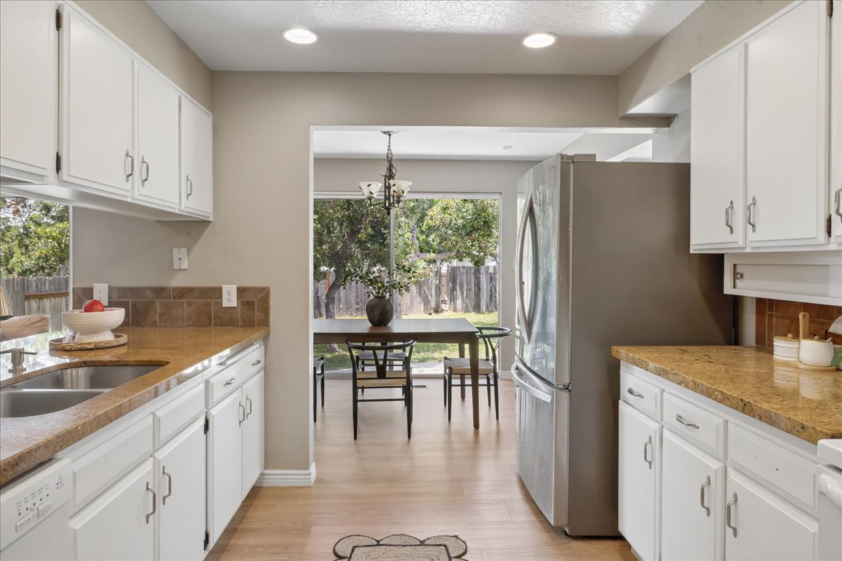 Galley kitchen with wood-finish flooring and white cabinetry