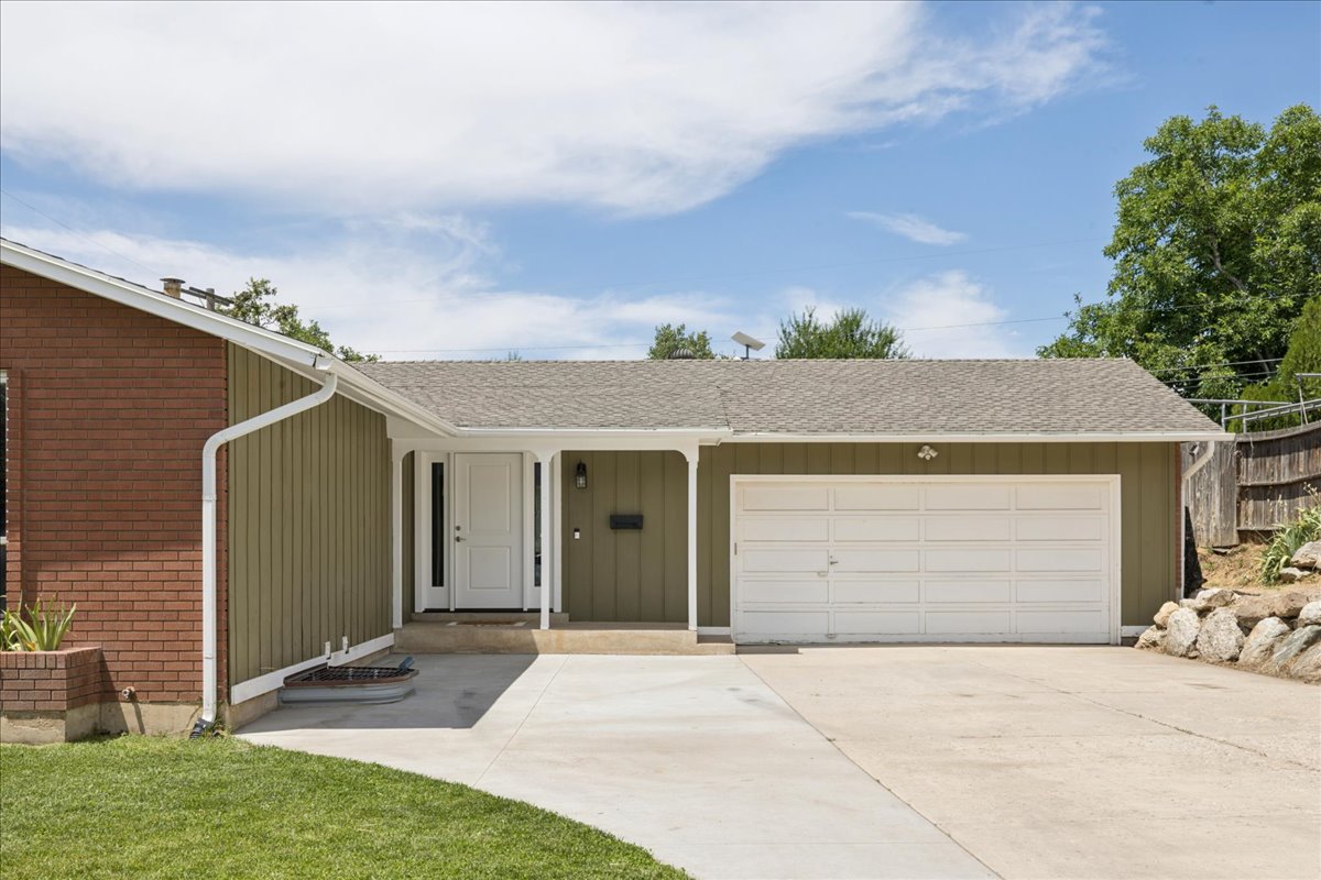 Exterior featuring brick and vertical siding, a two-car garage, and a covered entry
