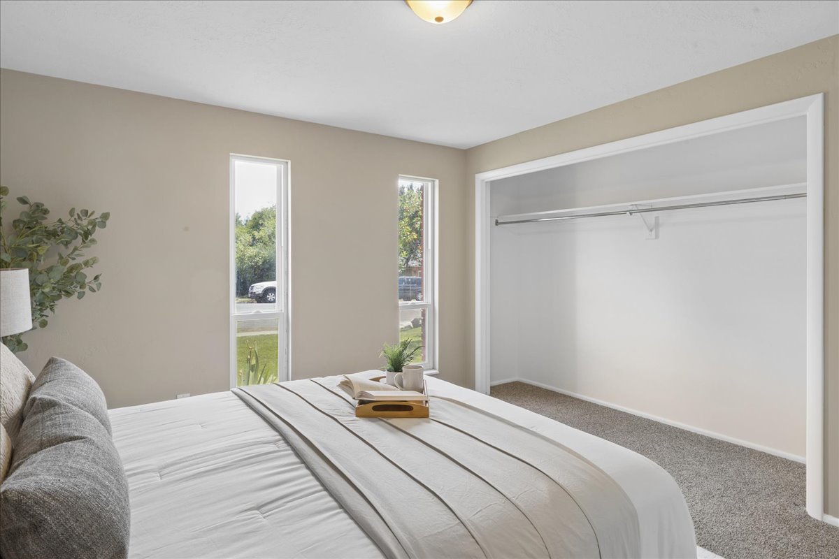Bedroom featuring two vertical windows, neutral wall tones, and a carpeted floor