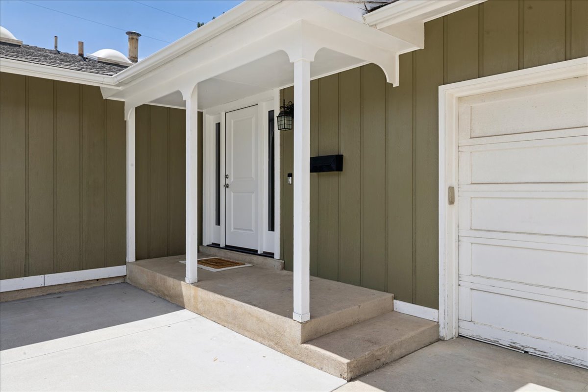 Covered entry porch featuring a white paneled door with sidelights, outdoor sconce lighting, and a mailbox