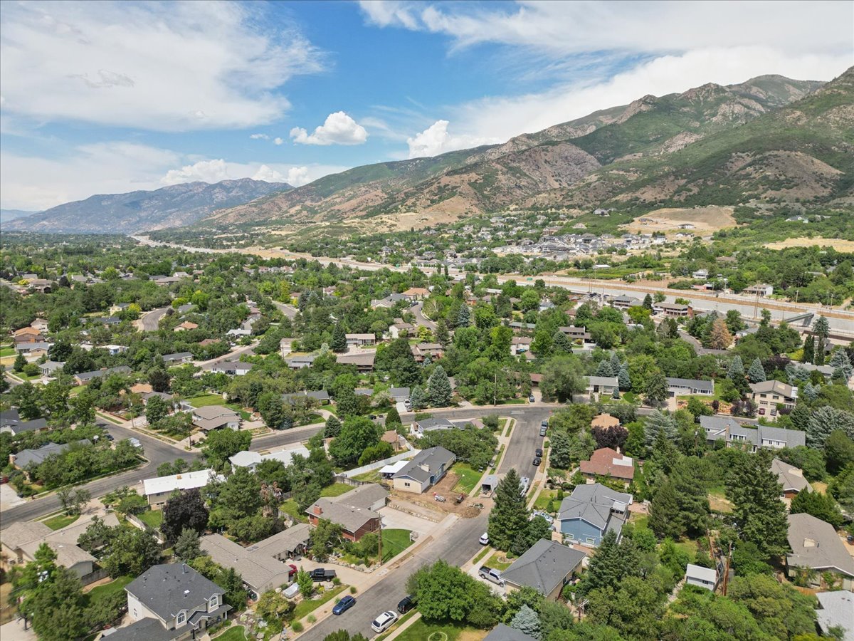 Expansive aerial perspective showcasing a residential area with lush tree coverage and surrounding mountainous terrain