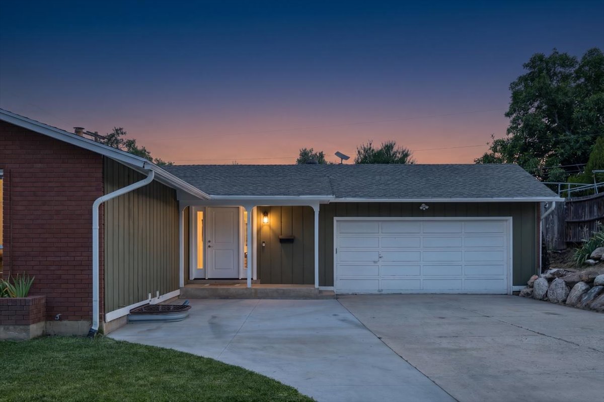 Single-story residence featuring brick and vertical siding, an attached two-car garage, a covered front entryway, and a paved driveway