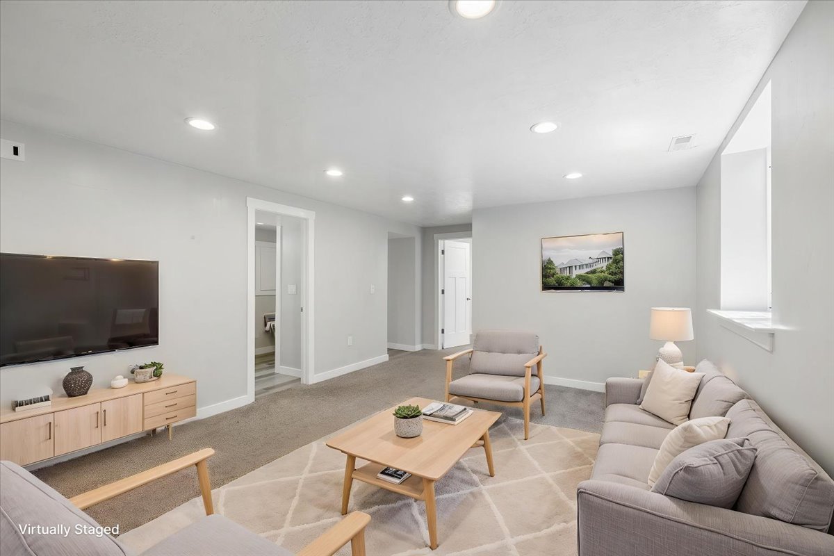 Spacious living area featuring neutral-toned walls, recessed lighting, and soft gray carpeting