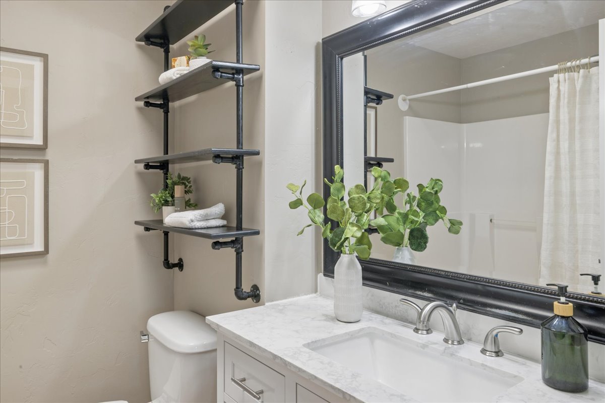 Bathroom featuring a white vanity with brushed nickel hardware, an integrated rectangular sink, and a stone-finish countertop