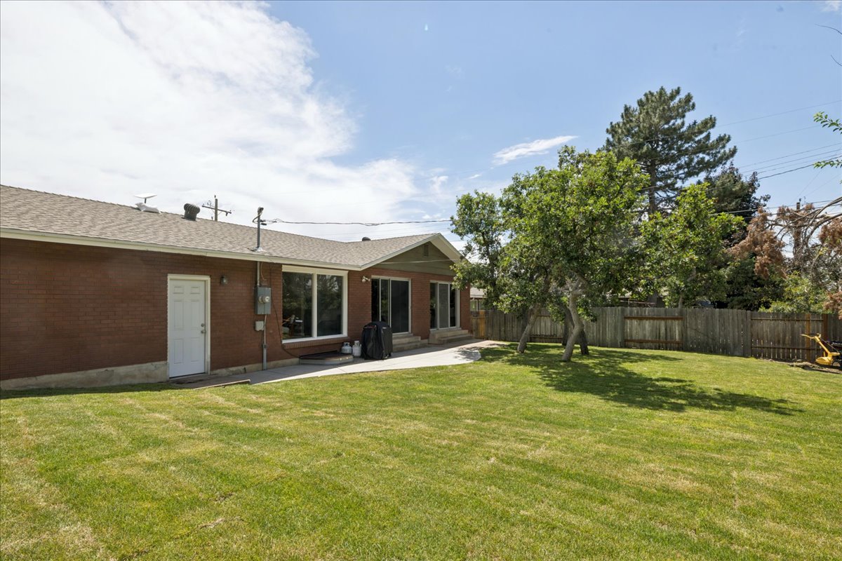 Expansive grassy yard featuring mature trees and a concrete patio