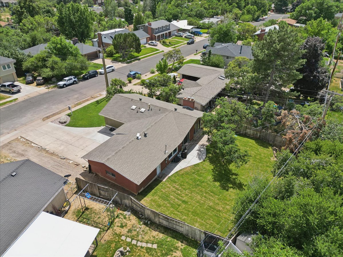 Expansive backyard featuring a manicured lawn, mature trees, and a wood fence