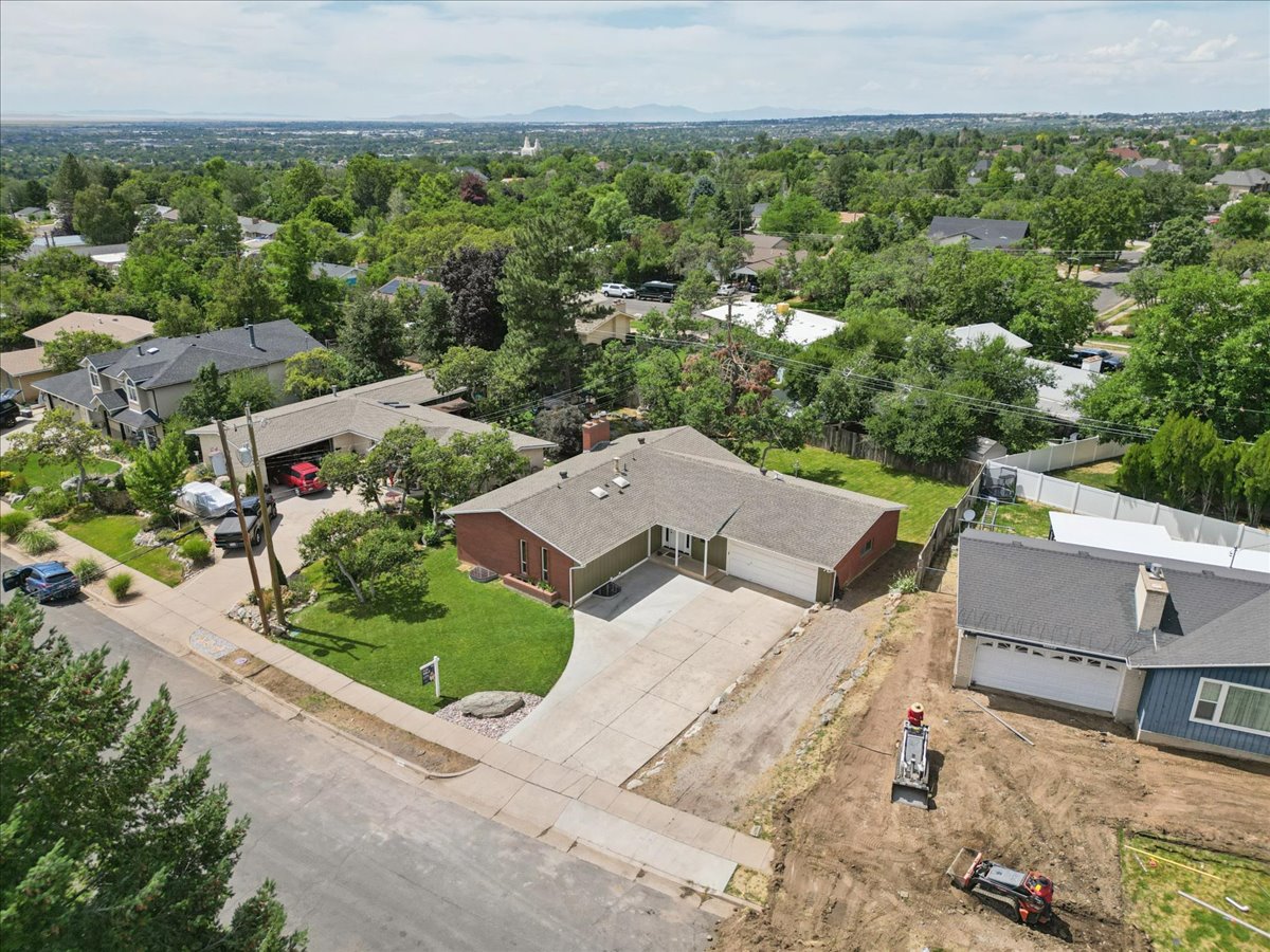 Ranch-style residence featuring a prominent two-car garage, mature landscaping, concrete driveway, and a shingle roof