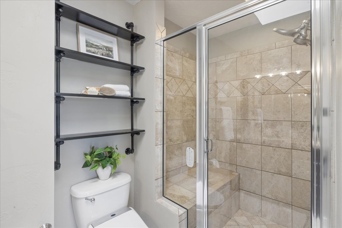 Walk-in shower with glass enclosure, integrated bench seating, and neutral-toned tile work featuring a decorative band