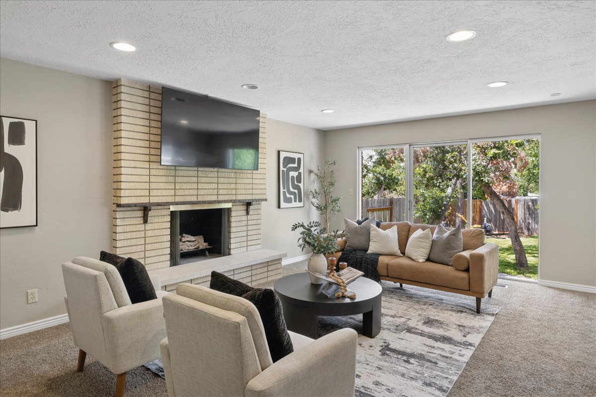 Living area featuring a brick fireplace with a stone hearth, recessed lighting, and sliding glass doors that open to the backyard
