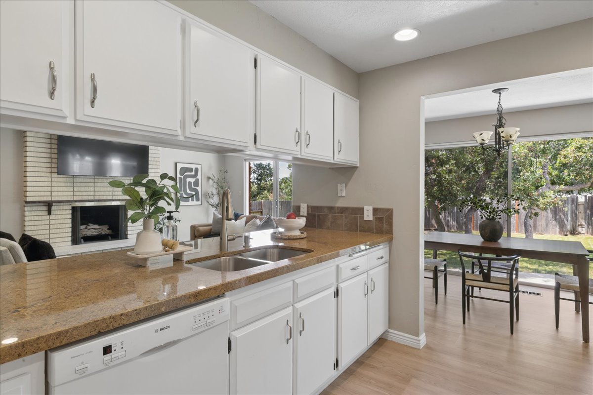 Kitchen featuring white cabinetry with brushed nickel hardware, a double basin stainless steel sink, and light brown speckled countertops