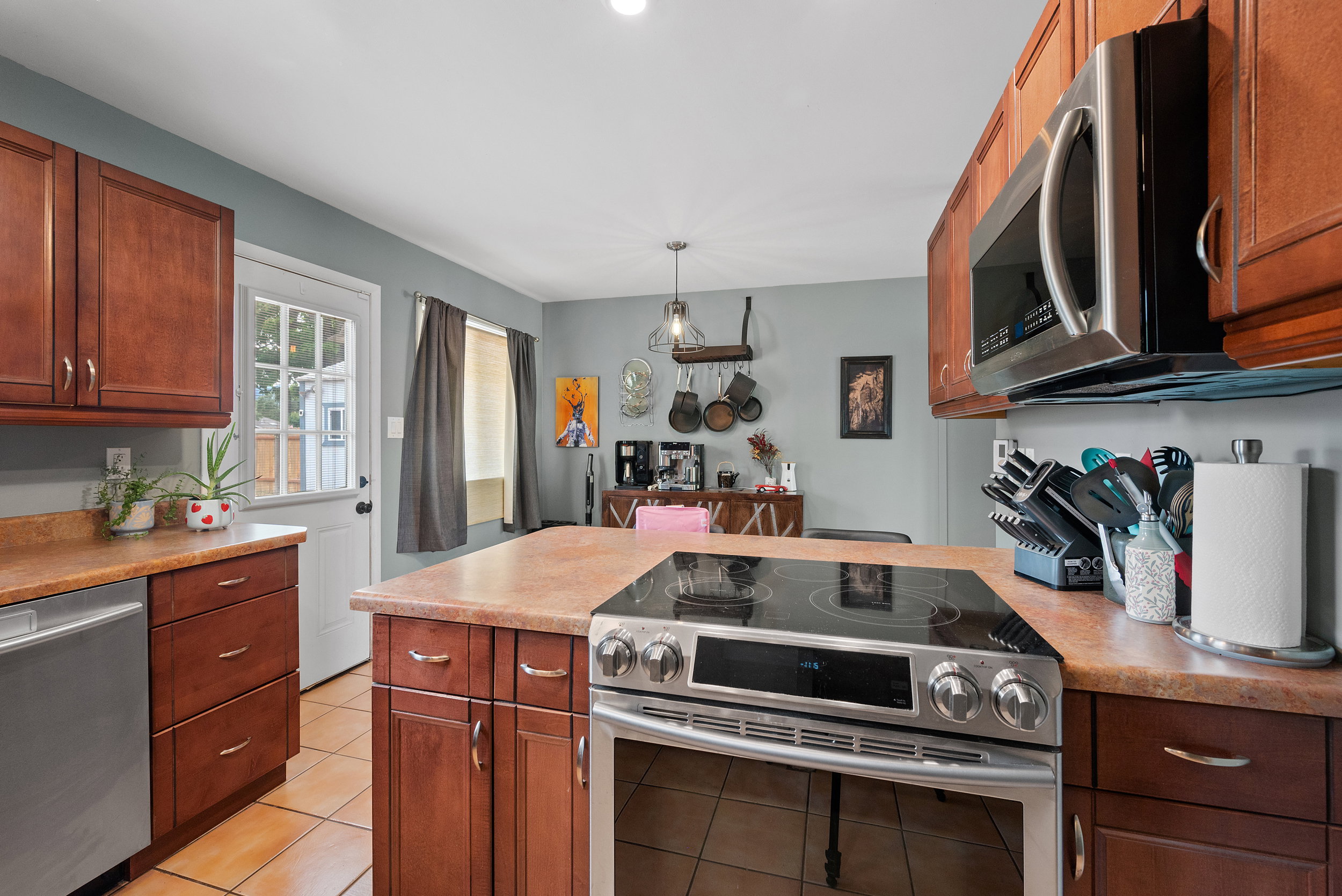 Contemporary kitchen featuring a stainless steel range with a flat cooktop, matching built-in microwave, and warm-toned cabinetry