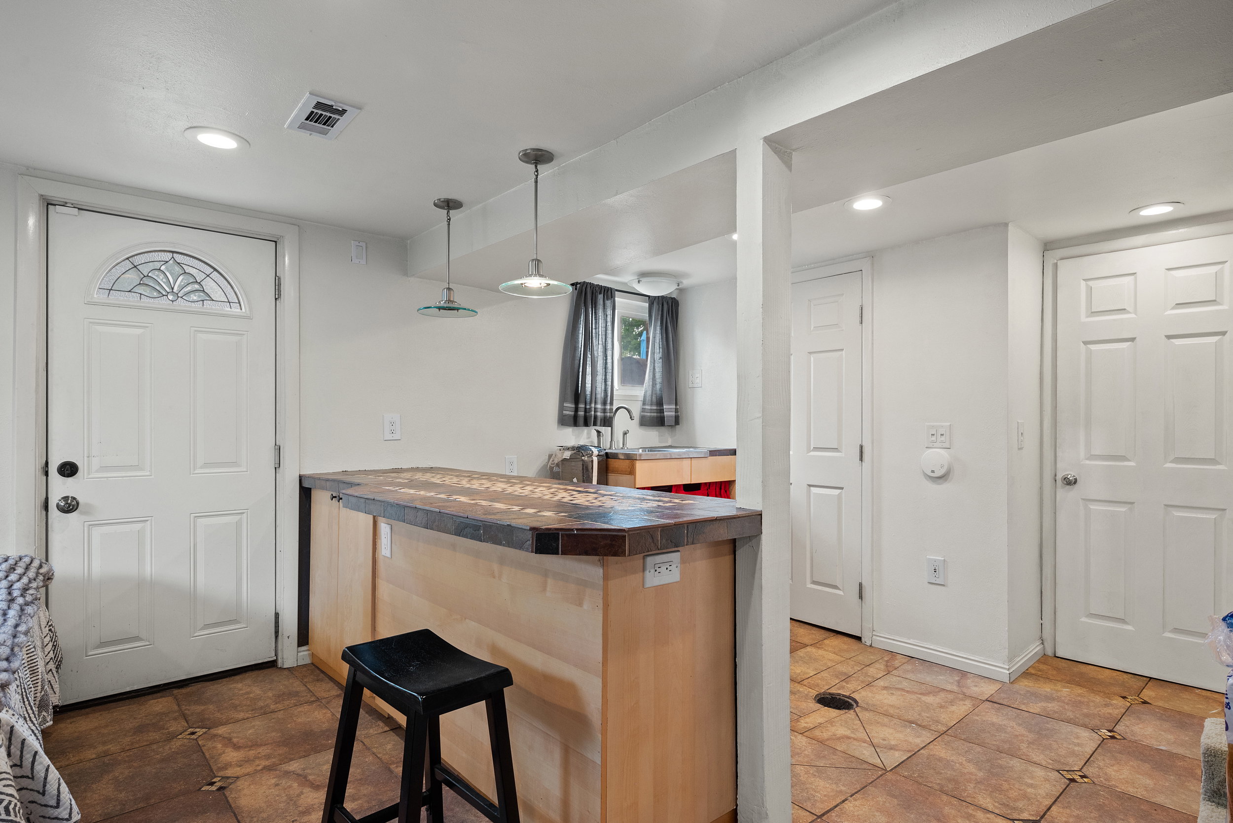 Kitchenette featuring a light wood-finish island with a dark countertop, two pendant lights, and recessed ceiling lighting
