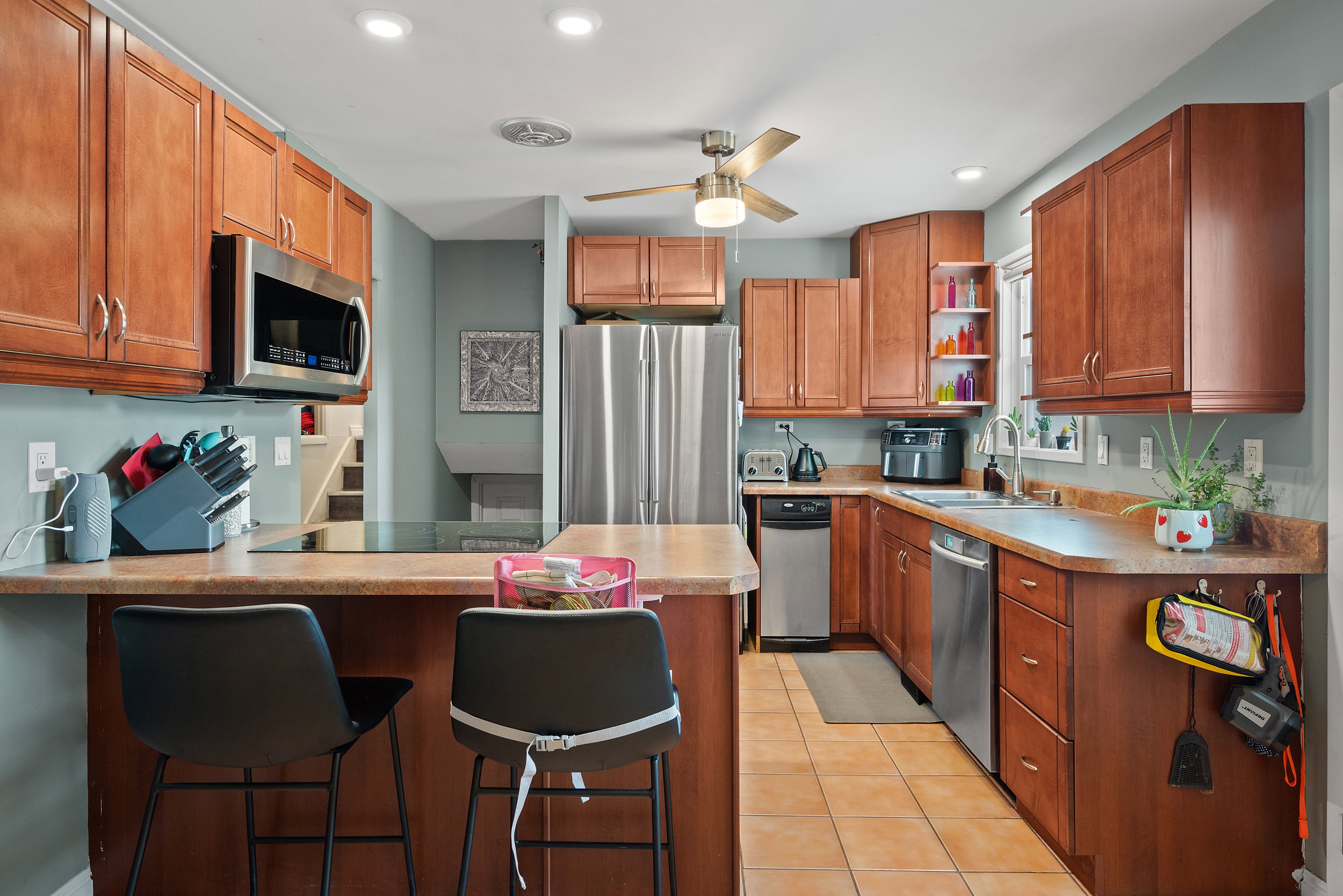 Modern kitchen featuring wood-finish cabinetry, stainless steel appliances, and a built-in cooktop with an overhead microwave