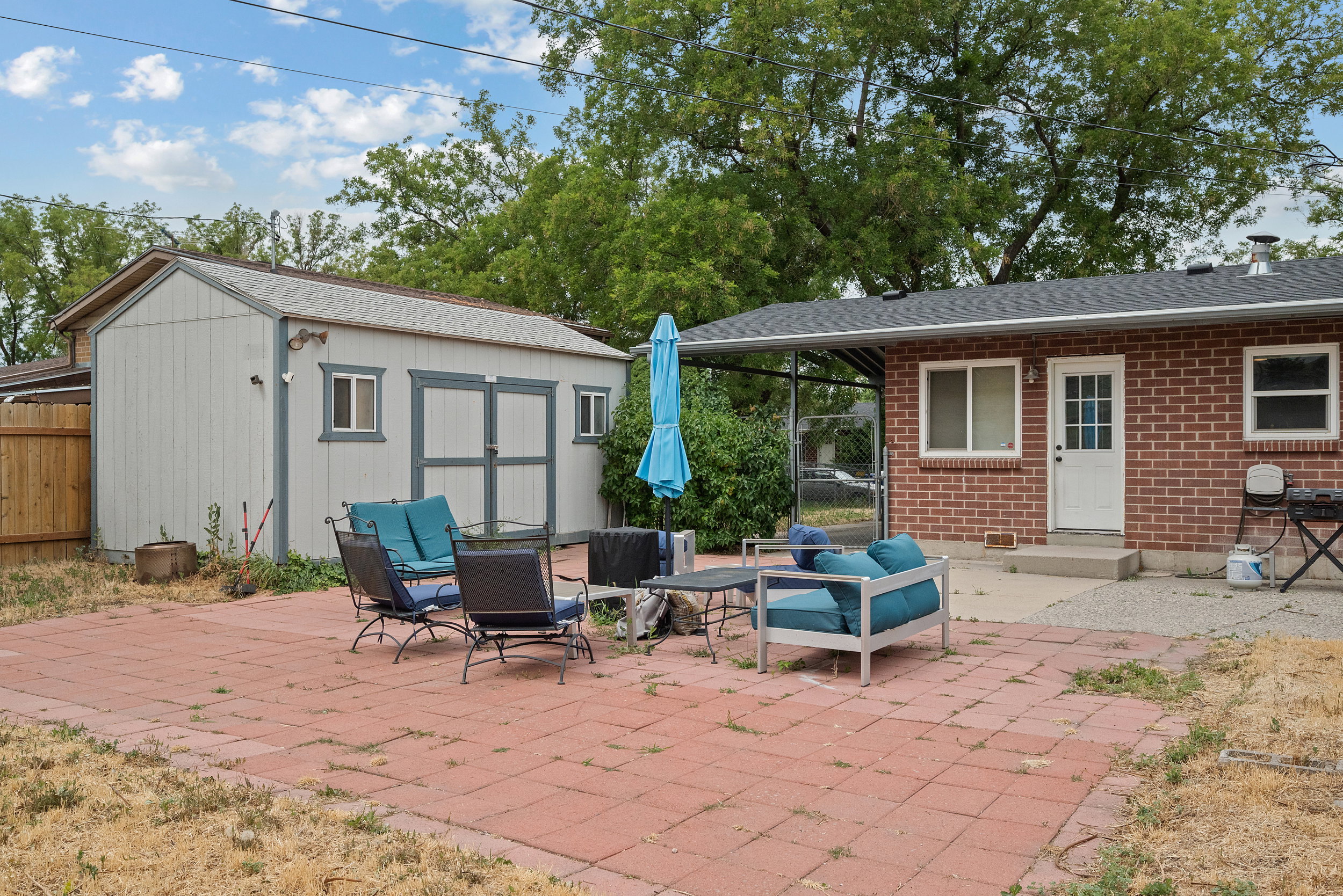 Expansive paver patio with a detached storage shed featuring double doors and side windows