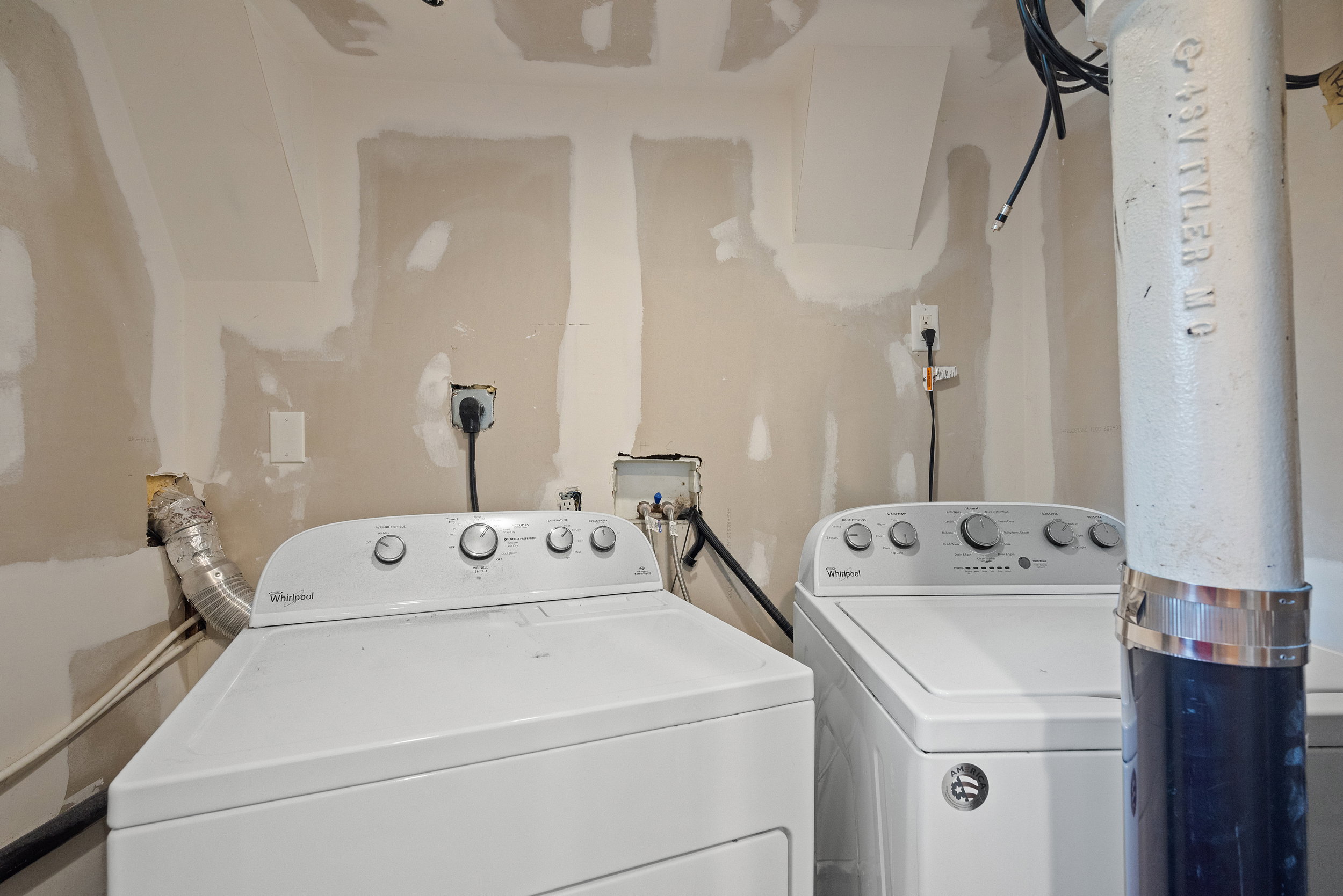 Dedicated laundry area featuring a white top-loading washing machine and a white front-loading dryer, with visible electrical outlets and plumbing connections