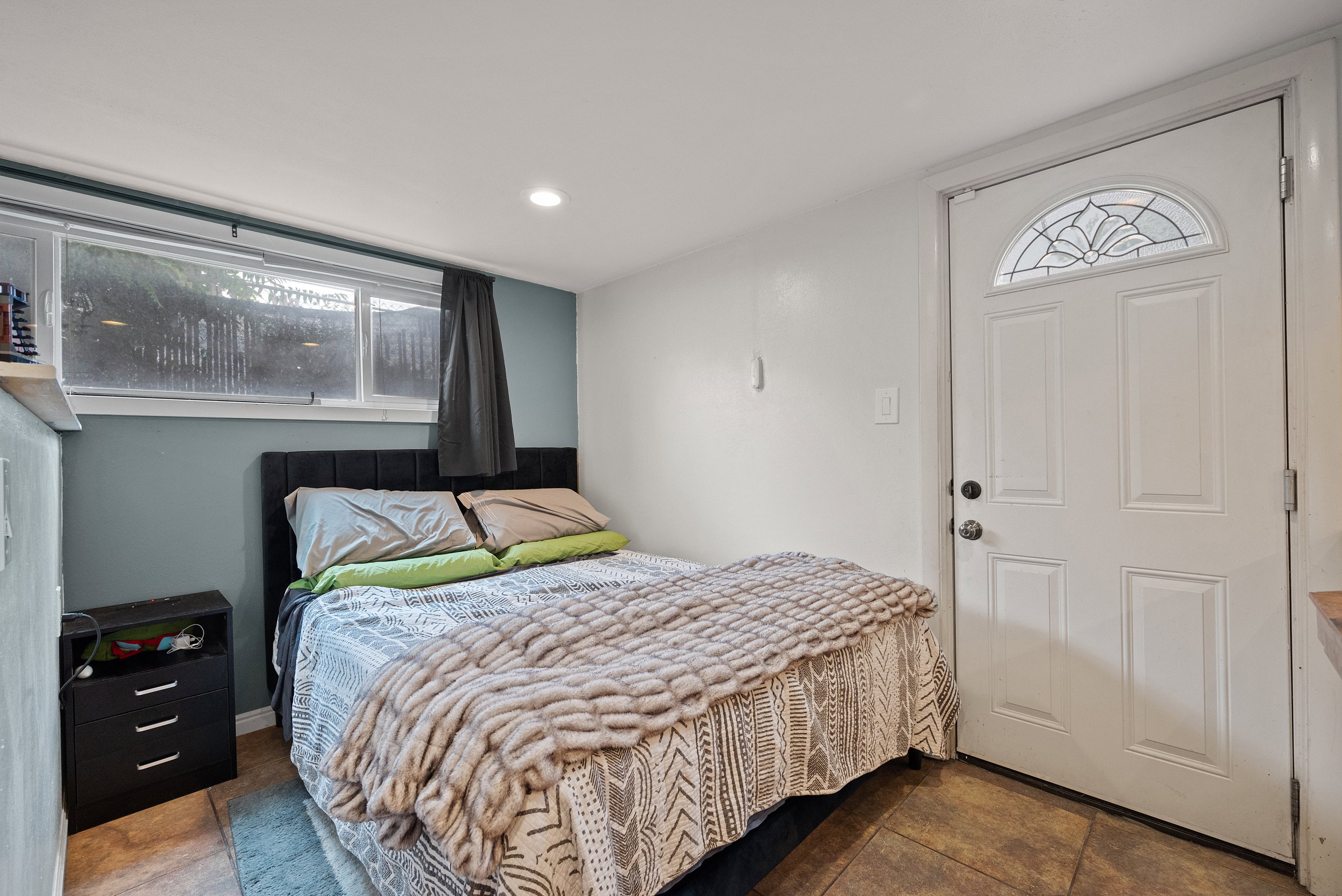 Room featuring tile flooring and a white paneled entry door with an arched decorative glass insert