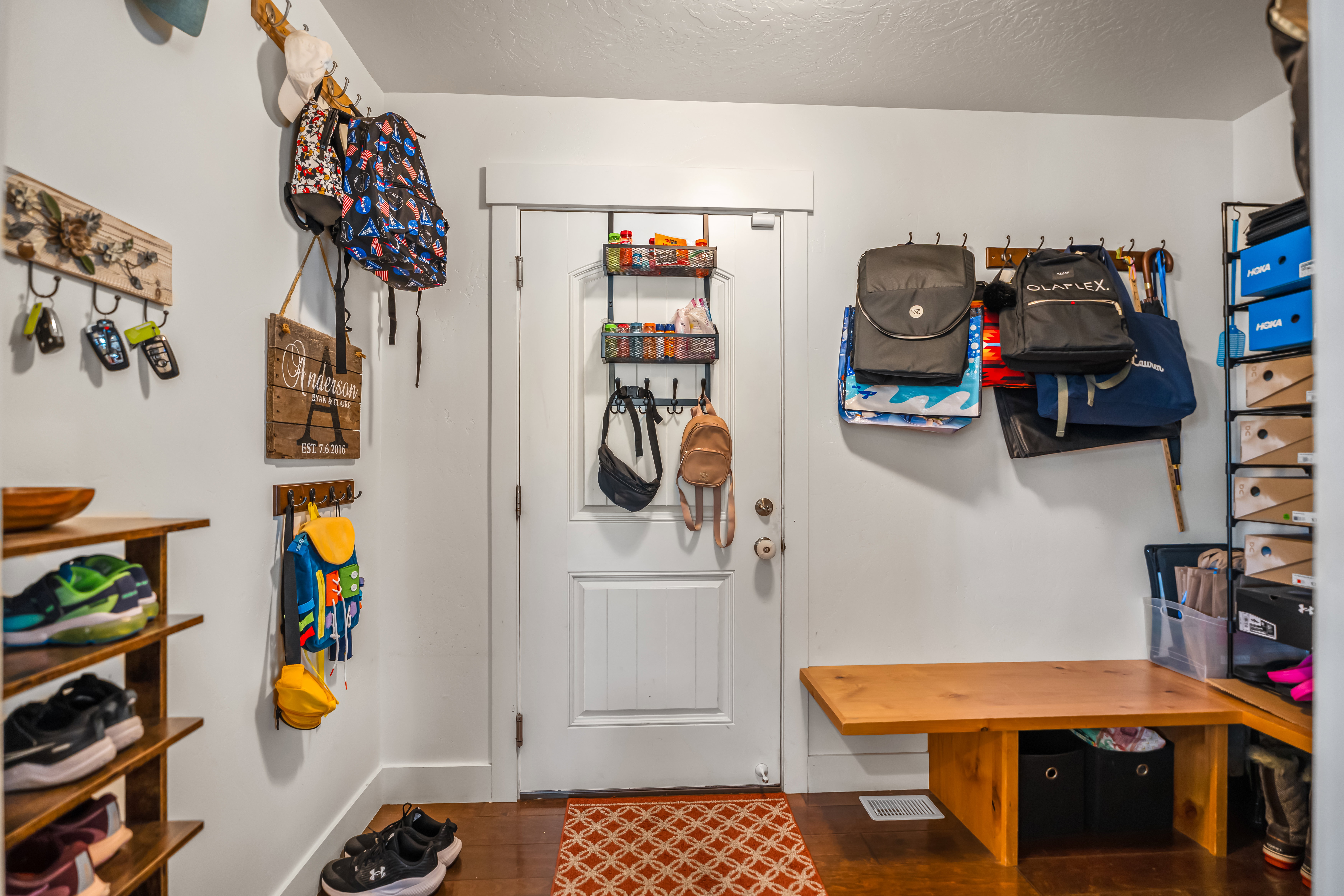 White paneled door with overhead storage, complemented by a built-in wood bench and warm-toned wood-finish flooring