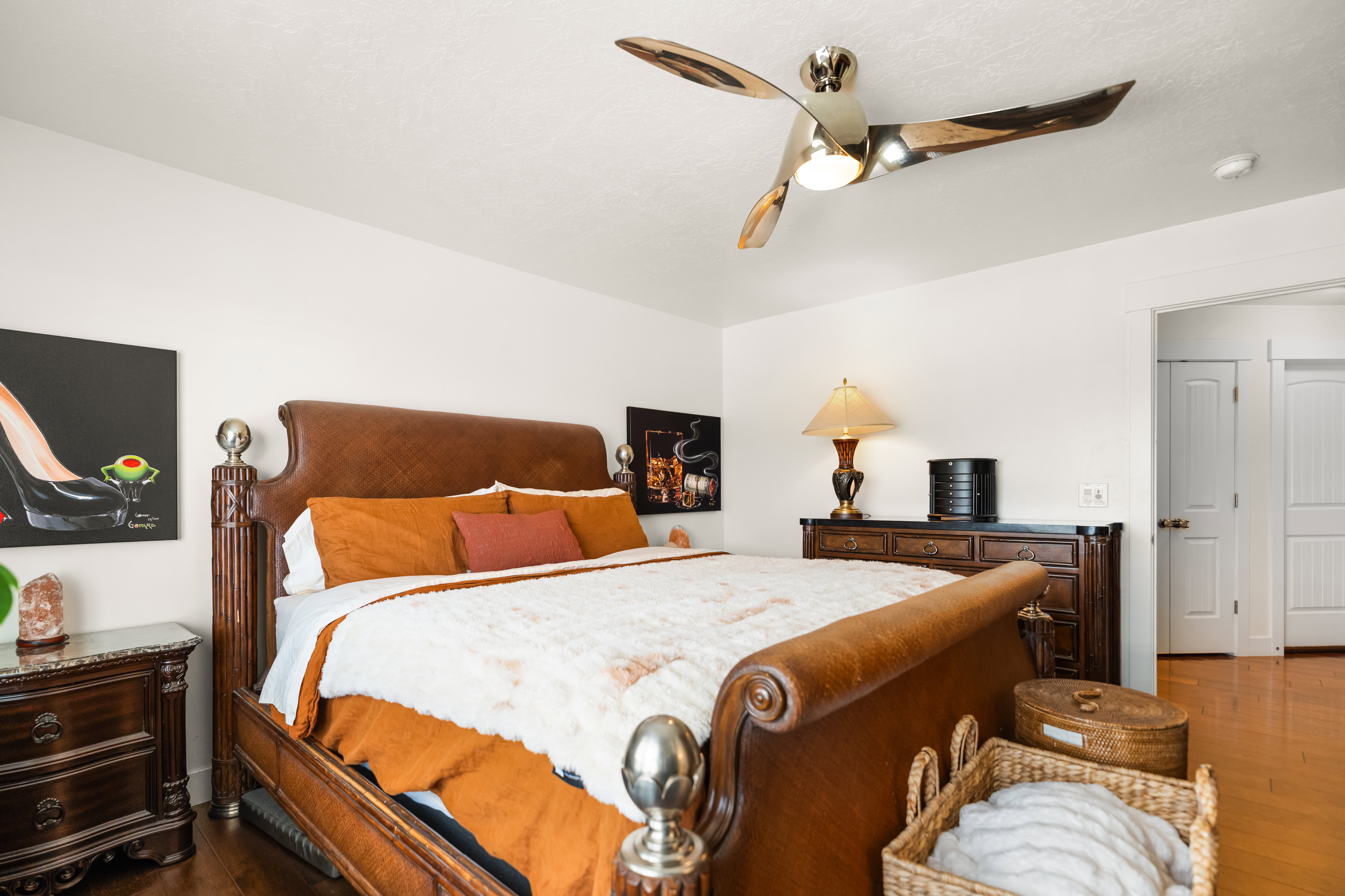 Hardwood-finish flooring complements white walls in this room, featuring an overhead ceiling fan with integrated lighting