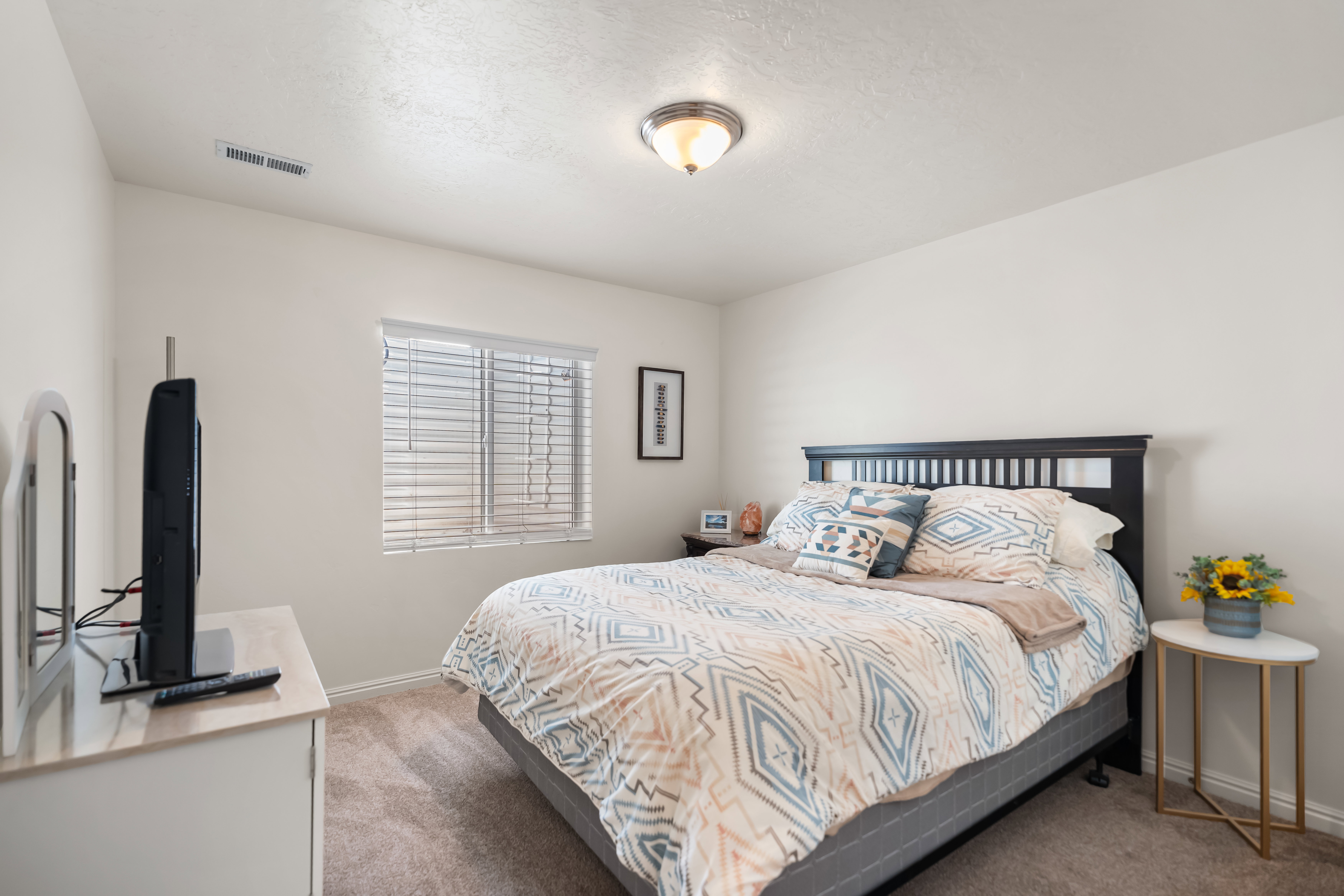 Bedroom featuring neutral wall paint, textured carpeting, a single window with blinds, and a flush-mount ceiling light fixture