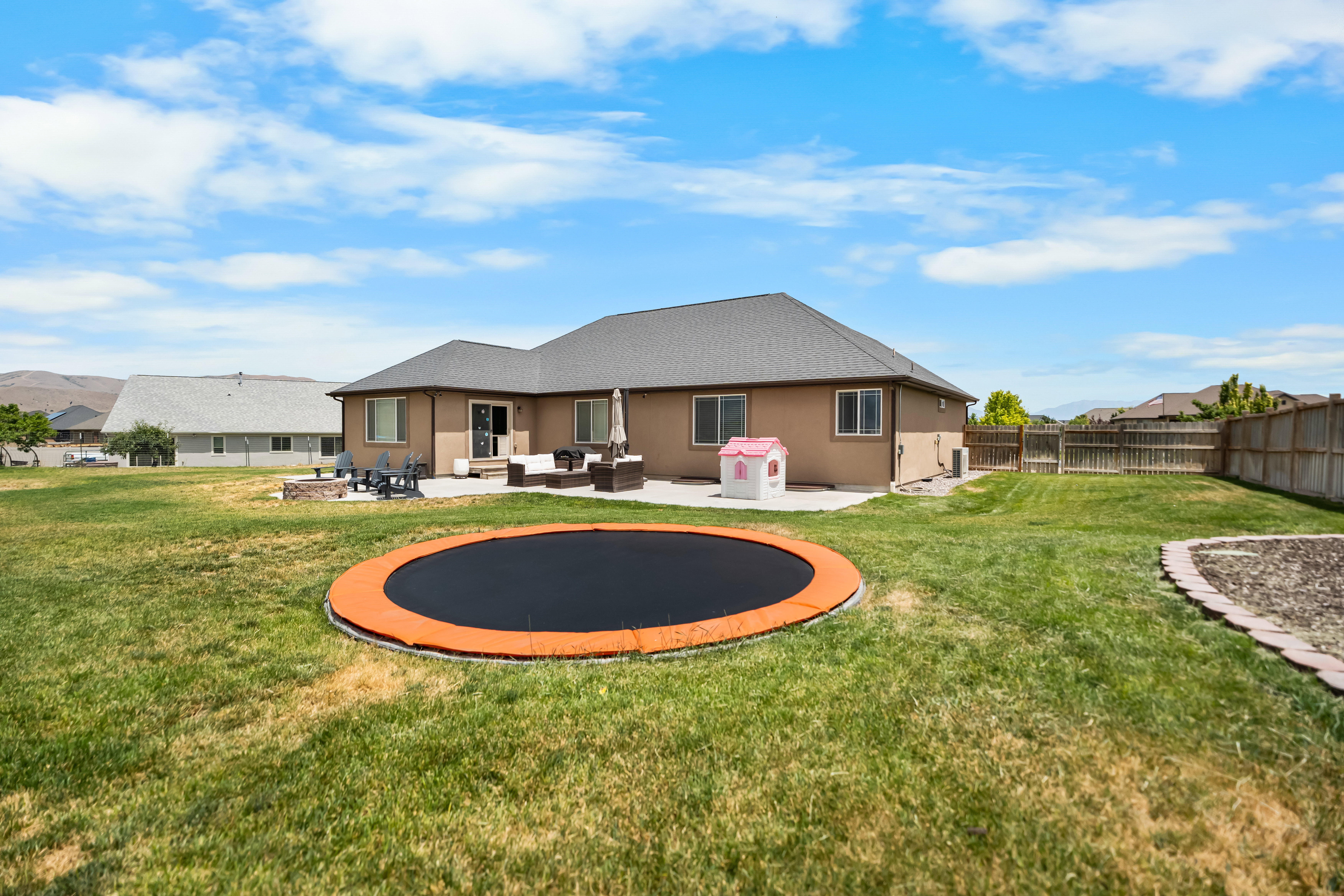 Spacious backyard featuring a large concrete patio, a built-in fire pit, and a wooden privacy fence