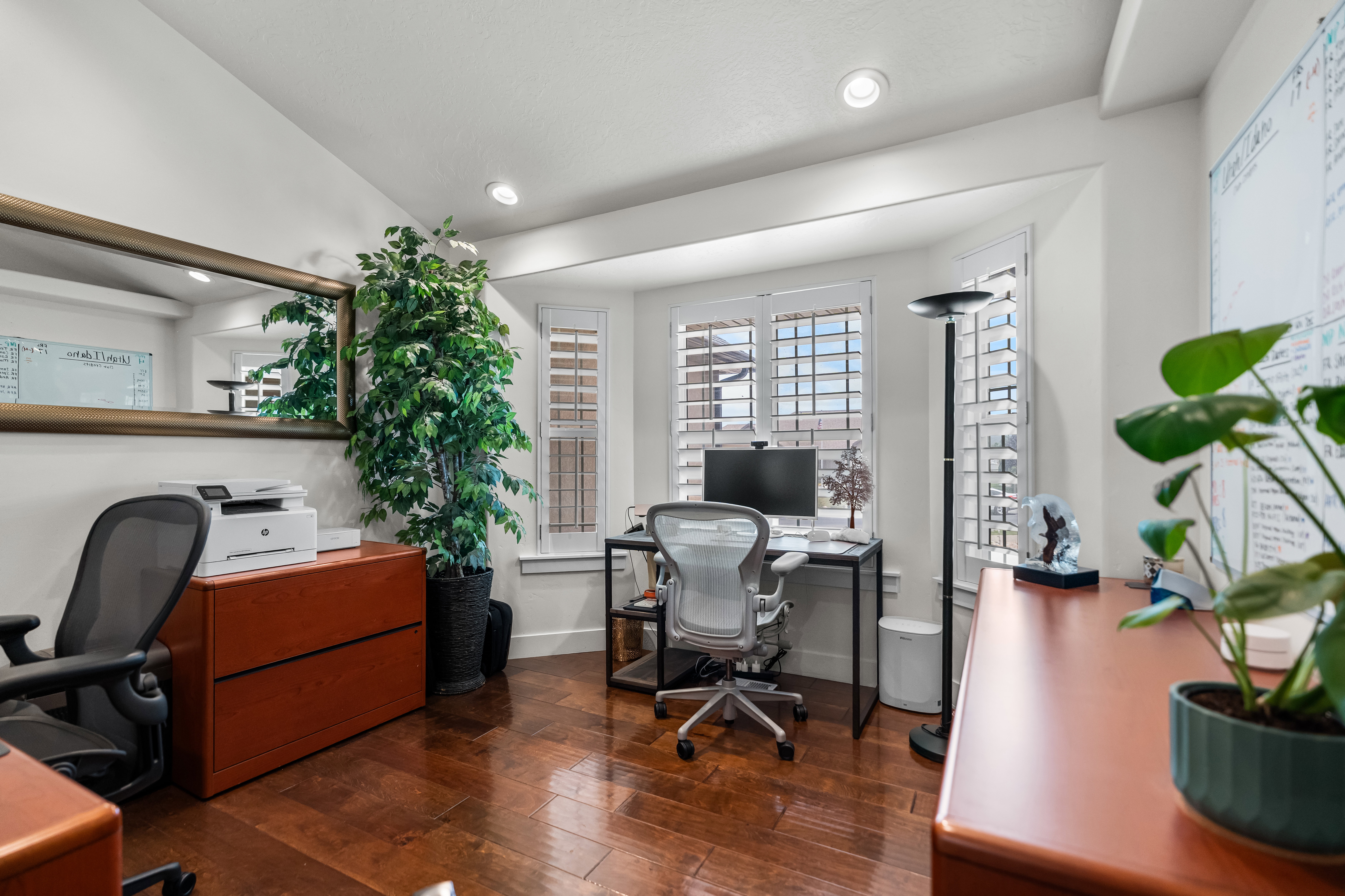 Dedicated office space featuring hardwood flooring, recessed lighting, and bay windows with plantation shutters