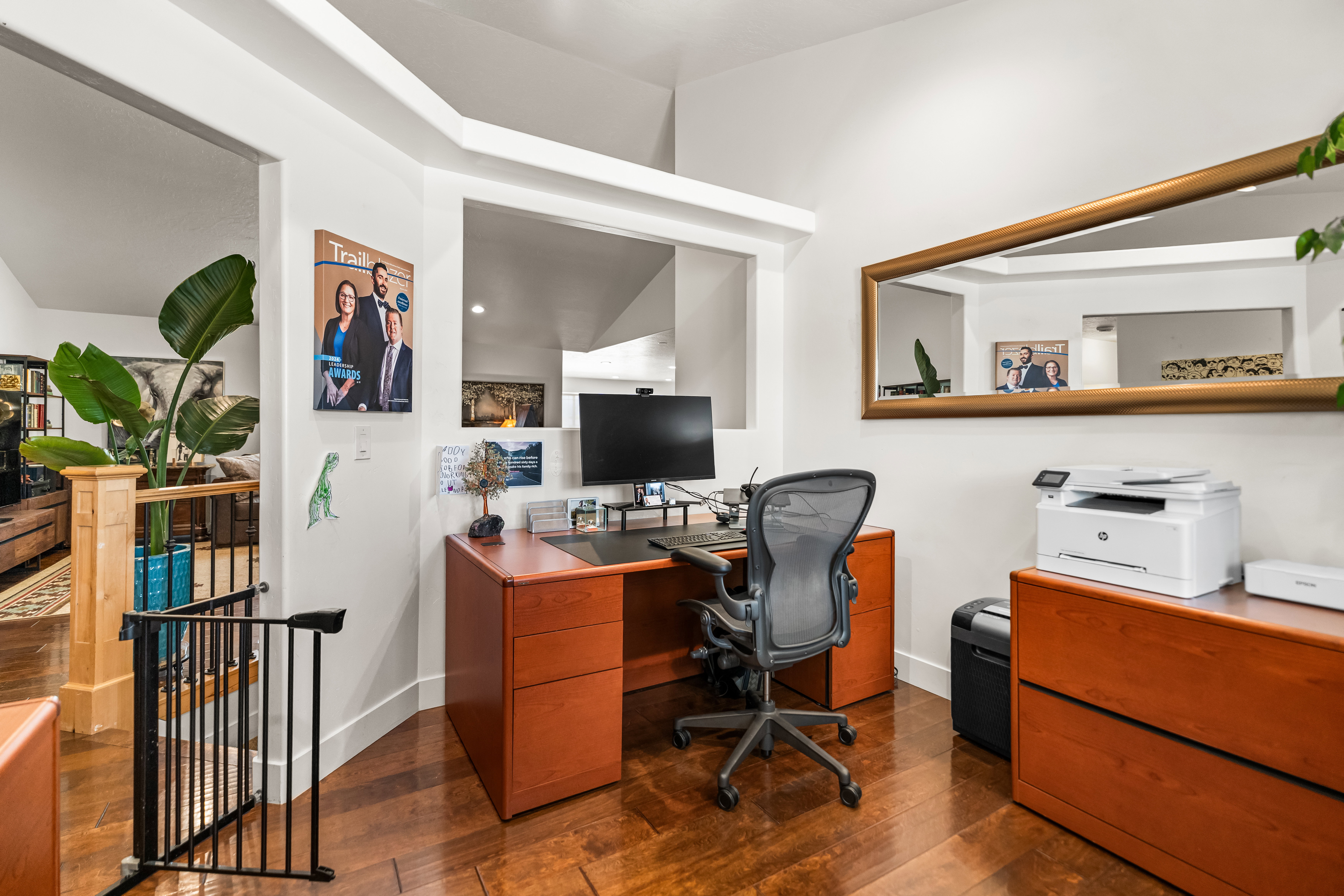 Dedicated office space featuring rich wood-finish flooring, a built-in wood-tone desk, a complementary wood-tone filing cabinet, and recessed ceiling lighting